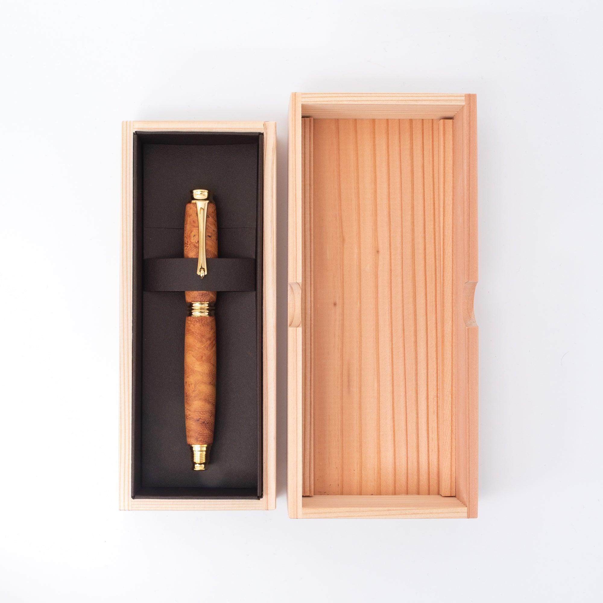 A Japanese Karin wood fountain pen with gold details, elegantly placed inside a wooden box with black lining, emphasizing its premium presentation.