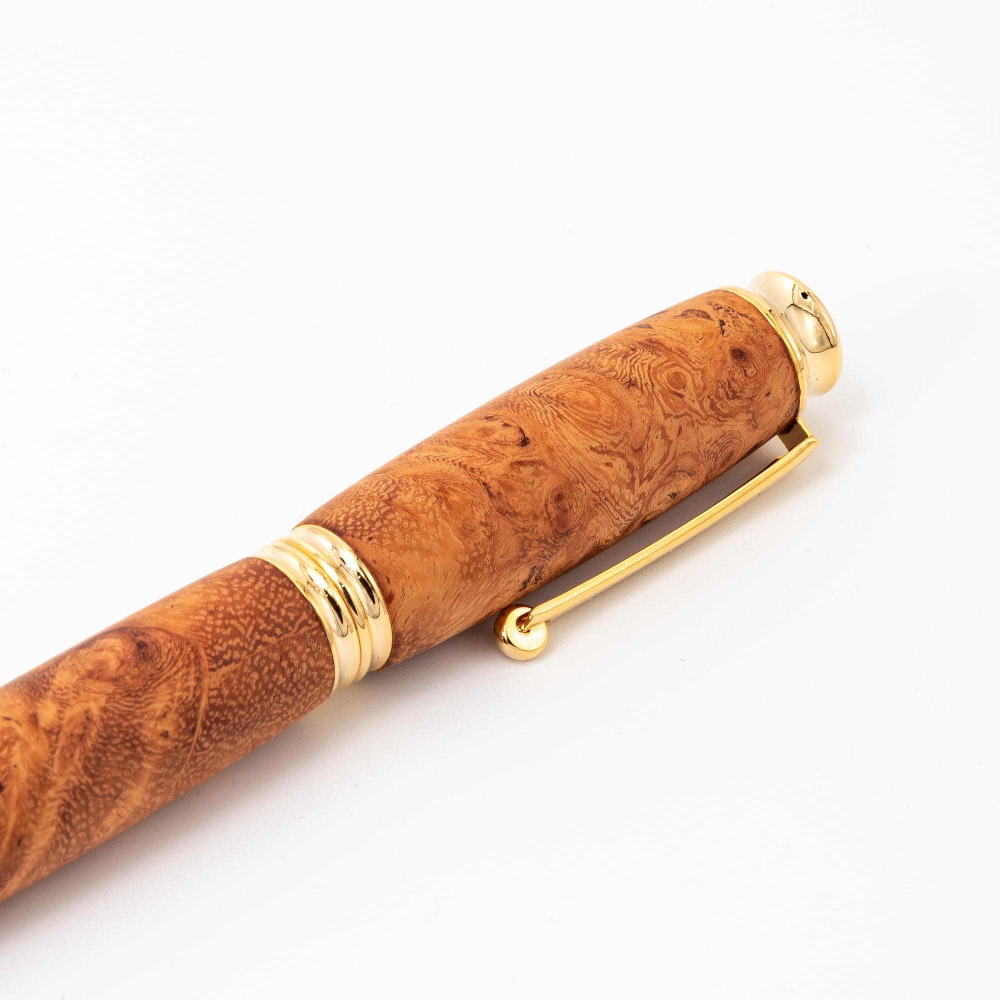 A close-up of a Japanese fountain pen featuring a richly grained Karin wood barrel and gold clip, displayed against a clean white background.