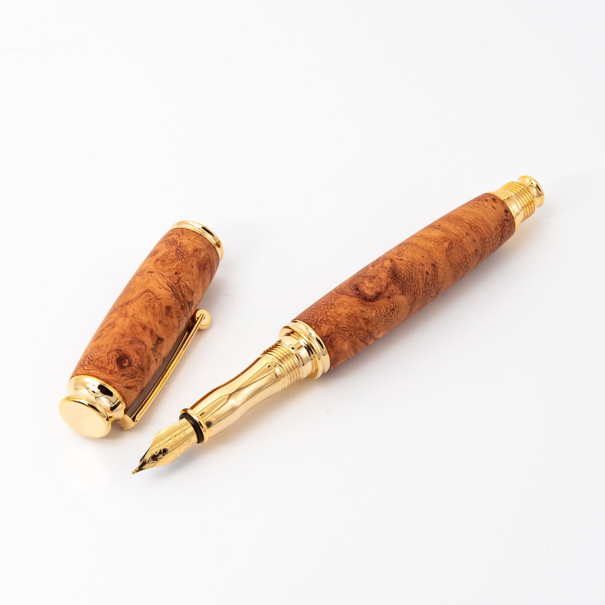 A Japanese fountain pen made of richly patterned Karin wood with gold accents, displayed open to highlight its nib and detachable cap on a white background.