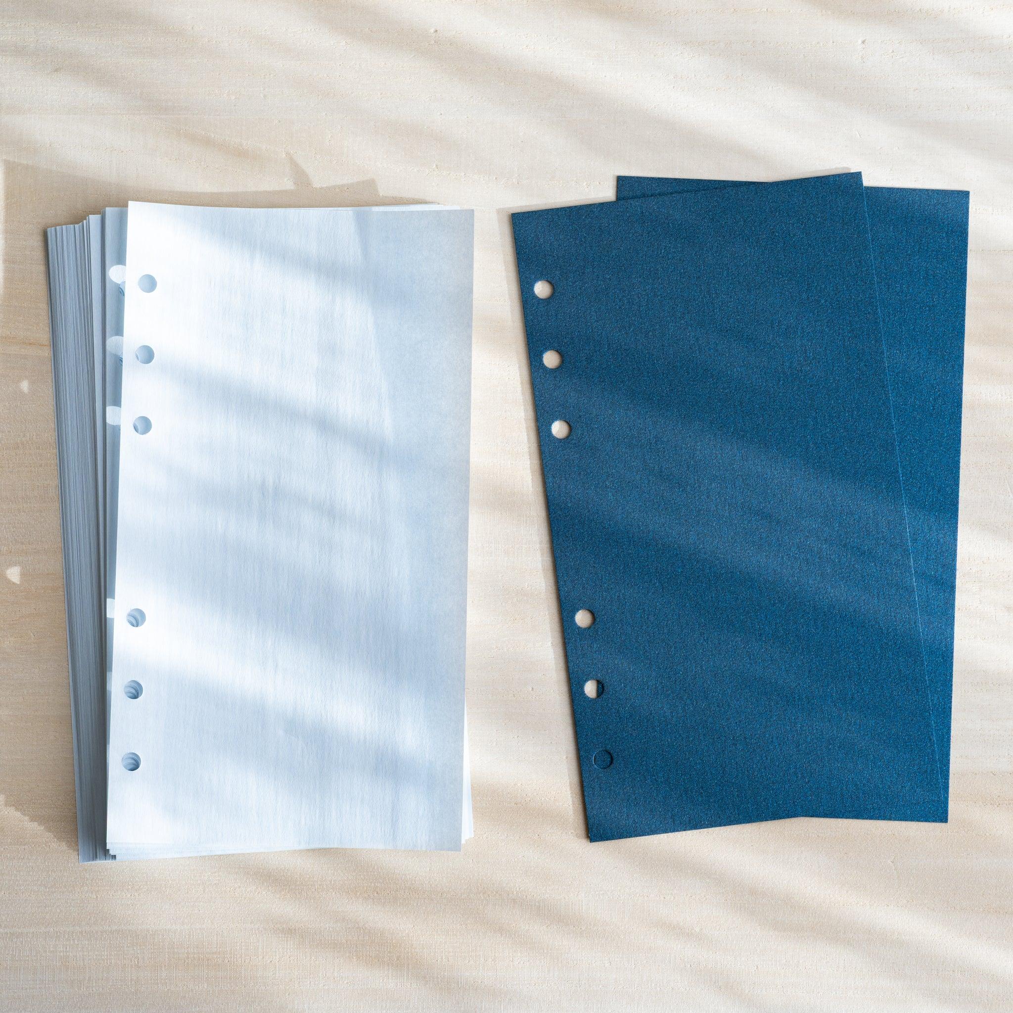 Two Japanese Stationery onion skin refill stacks in pale blue and navy, both six-hole punched and laid flat on a light desk.