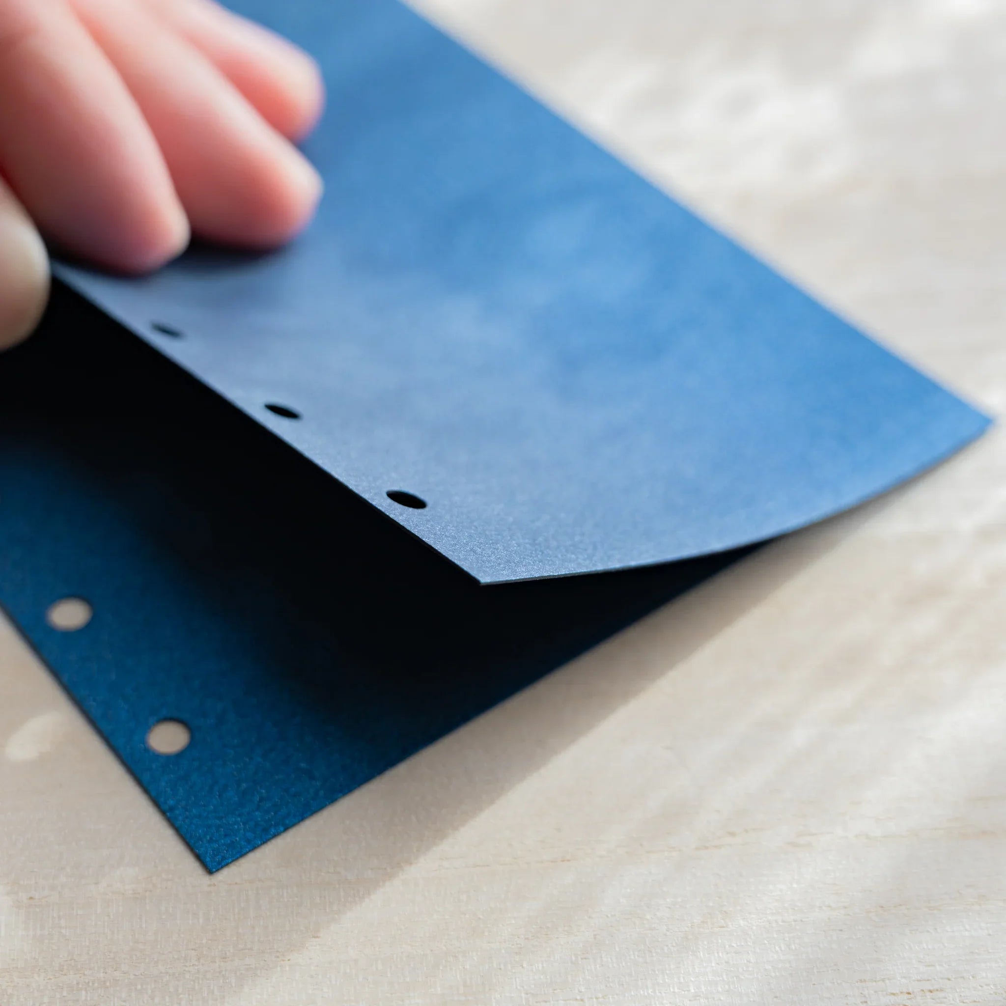 Japanese Stationery blue onion skin refill sheet held up close, showing thin texture and six-hole punches for mini 6 planners.