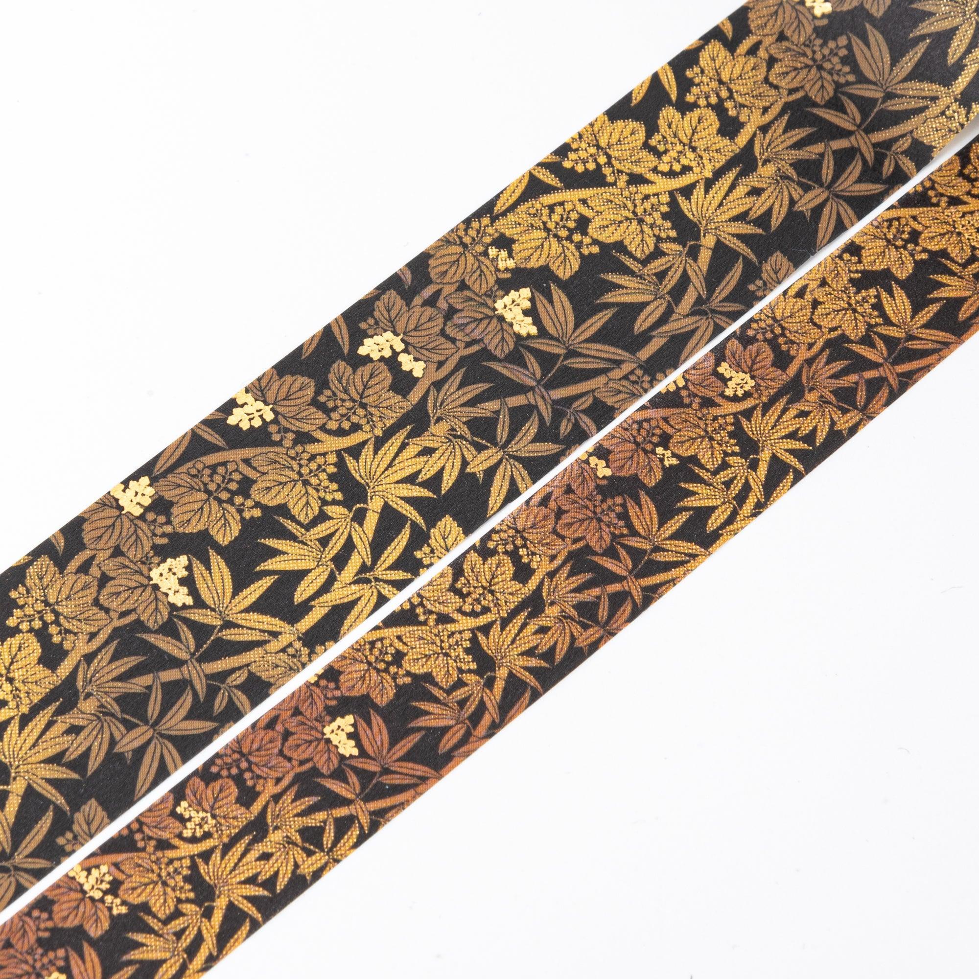 Close-up of unrolled washi tape featuring gold and bronze bamboo leaf motifs on a black background for elegant decoration.