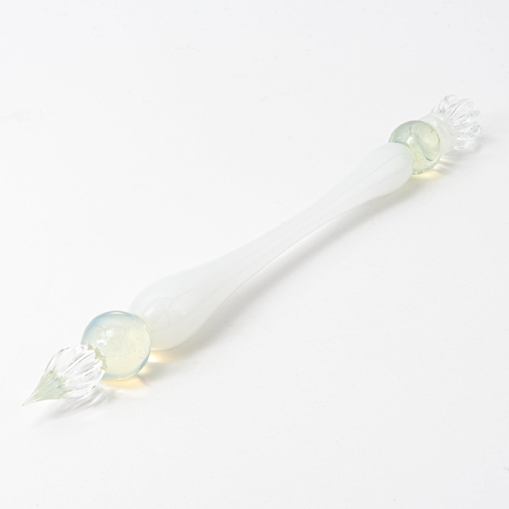 White glass pen with clear and blue spheres, elegantly poised on a pristine surface, perfect for stationery lovers.