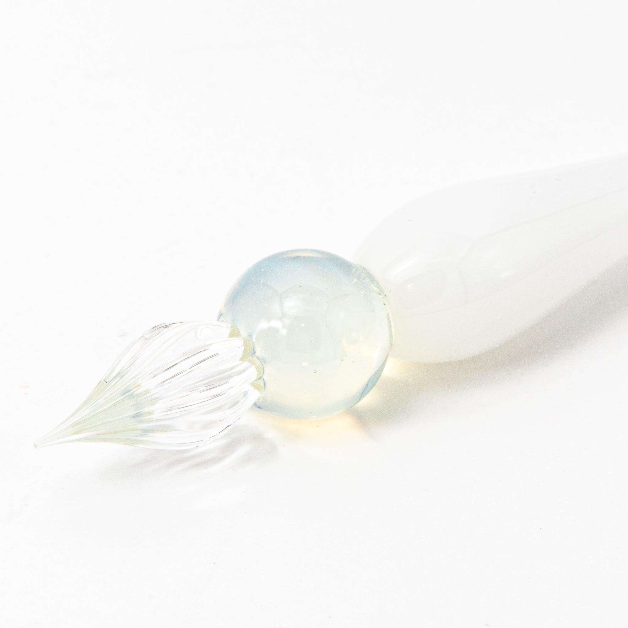 White glass pen with clear and blue spheres, elegantly poised on a pristine surface, perfect for stationery lovers.