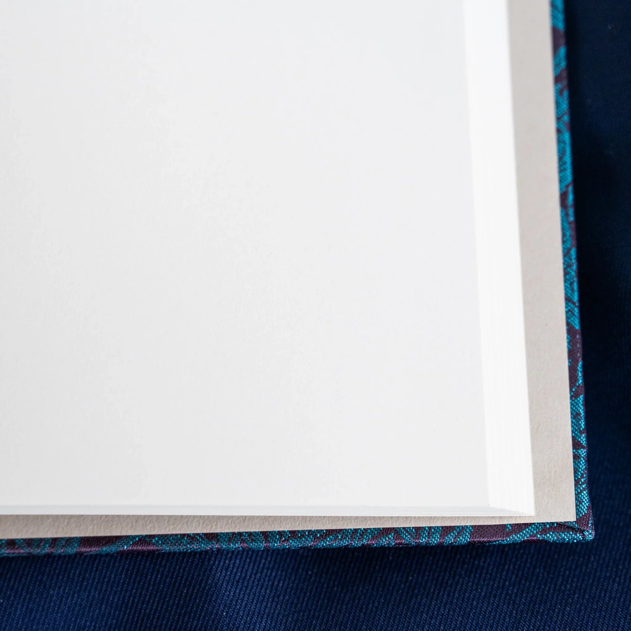 Kiri Take Ho-o Nishijin silk Homeicho notebook corner detail showing white page edges and teal woven cover binding