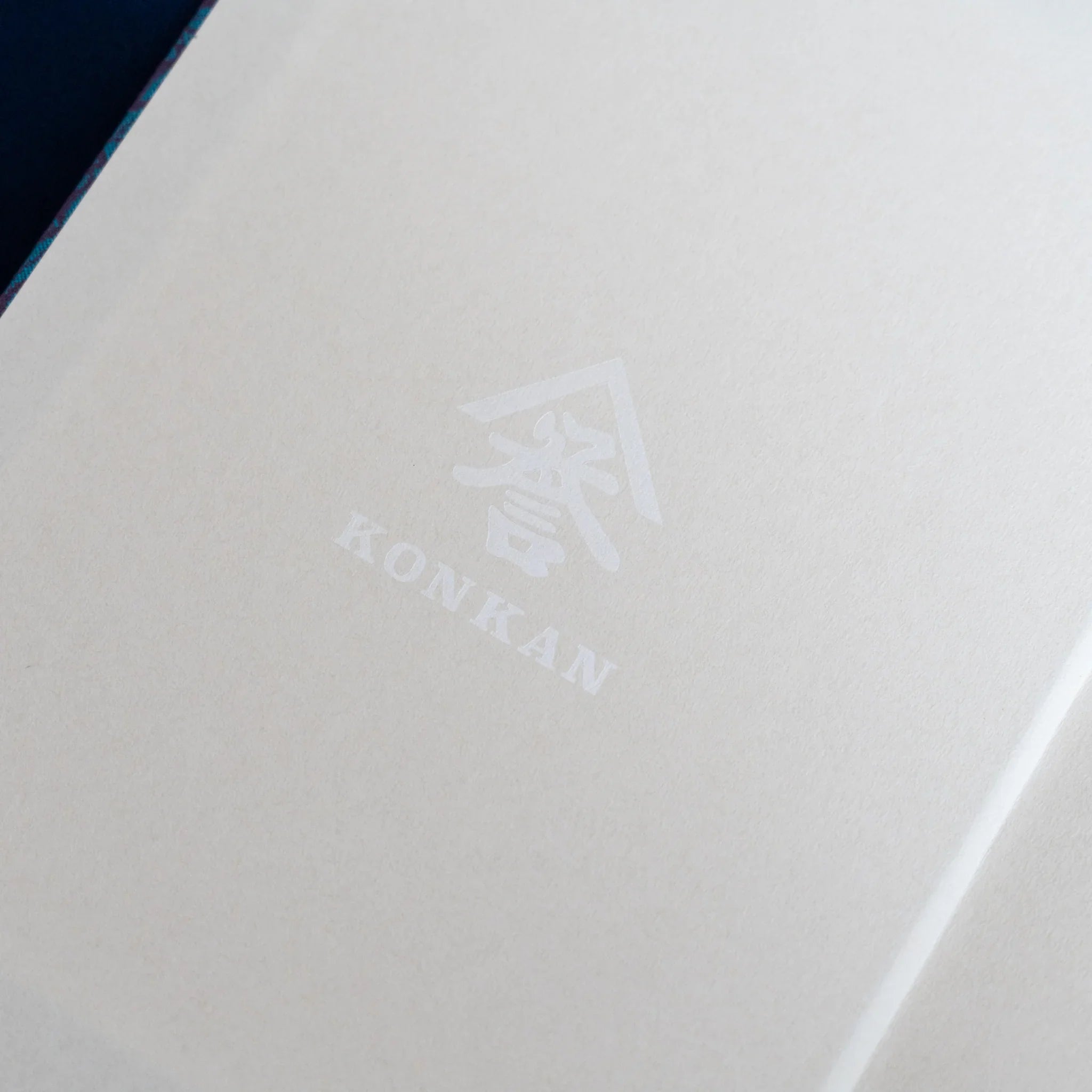 Kiri Take Ho-o Nishijin silk notebook interior page with Konkan watermark and teal silk cover corner visible