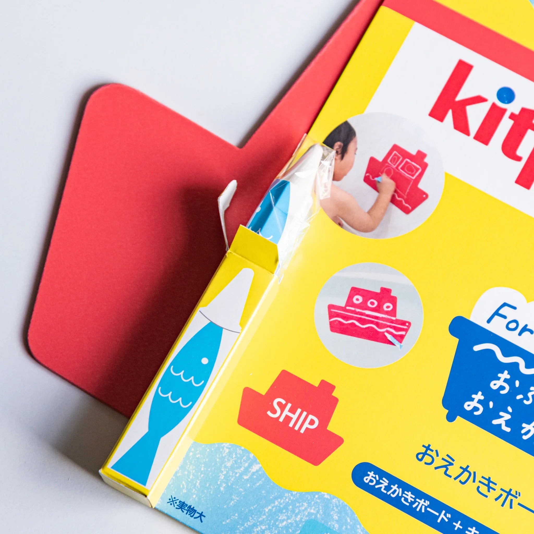 Kitpas bath drawing board kit packaging with a red ship board behind and a yellow box decorated with ship and fish illustrations.