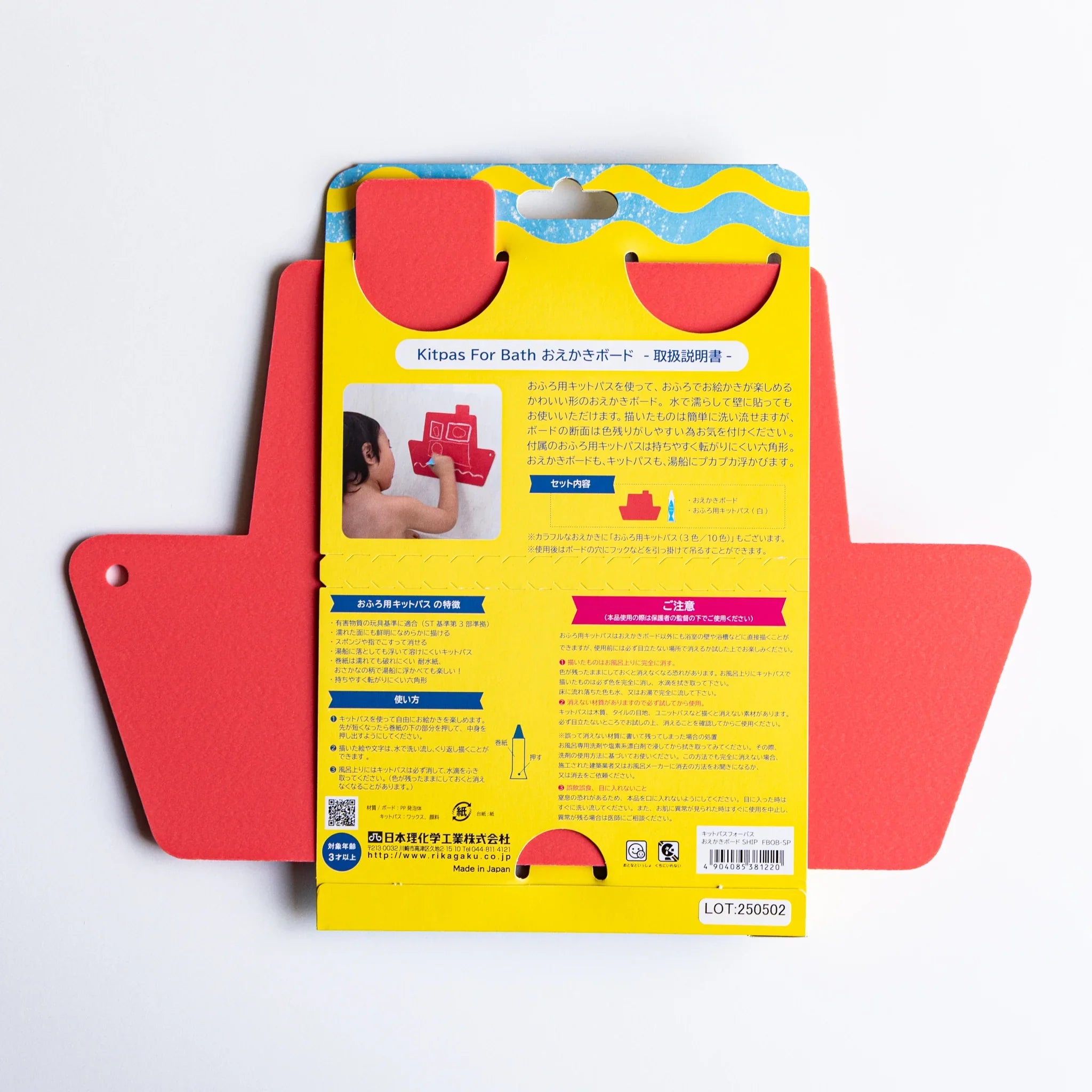 Red ship-shaped kitpas bath drawing board with the instruction sheet attached to the center on a white background.
