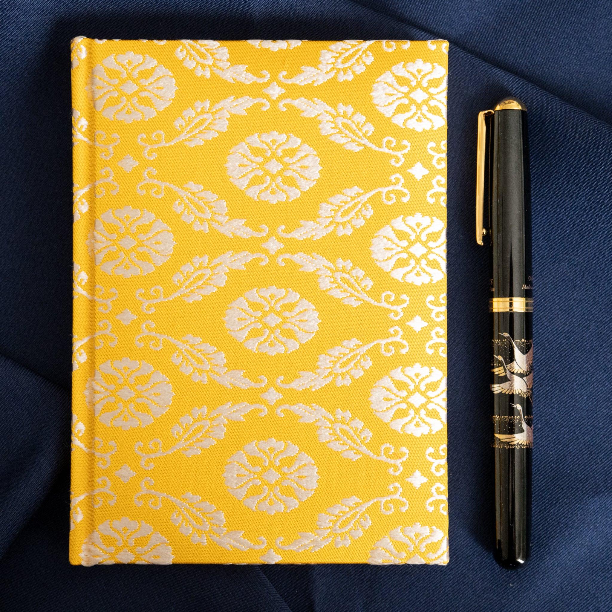 Ko Aoi Nishijin silk Homeicho notebook on navy fabric with black gold fountain pen standing beside the golden Ko Aoi cover