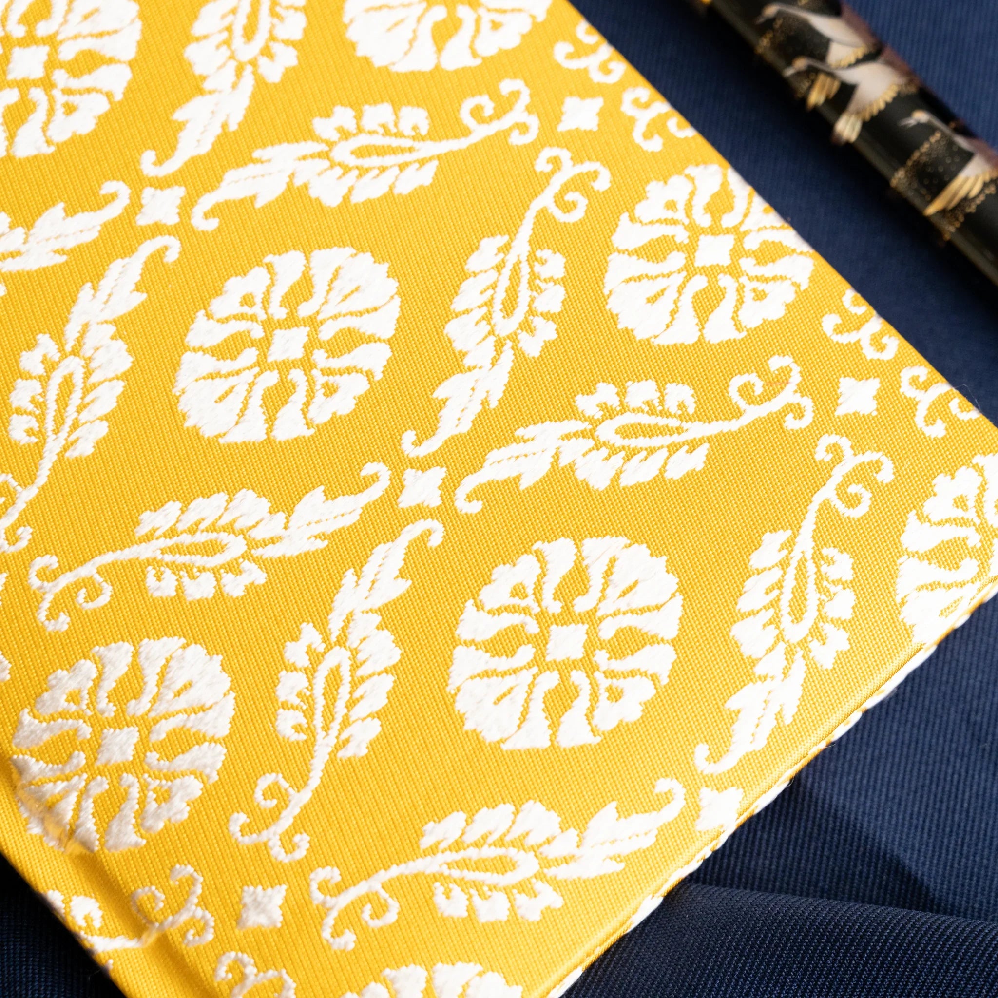 Ko Aoi Nishijin silk notebook angled corner detail showing golden Ko Aoi cover weave with fountain pen visible at top right