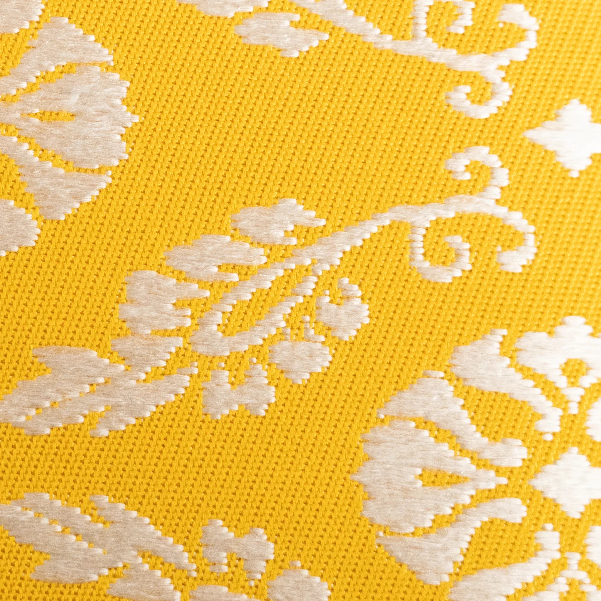 Macro detail of Ko Aoi Nishijin silk showing golden yellow woven threads with raised cream leaf and scroll motifs