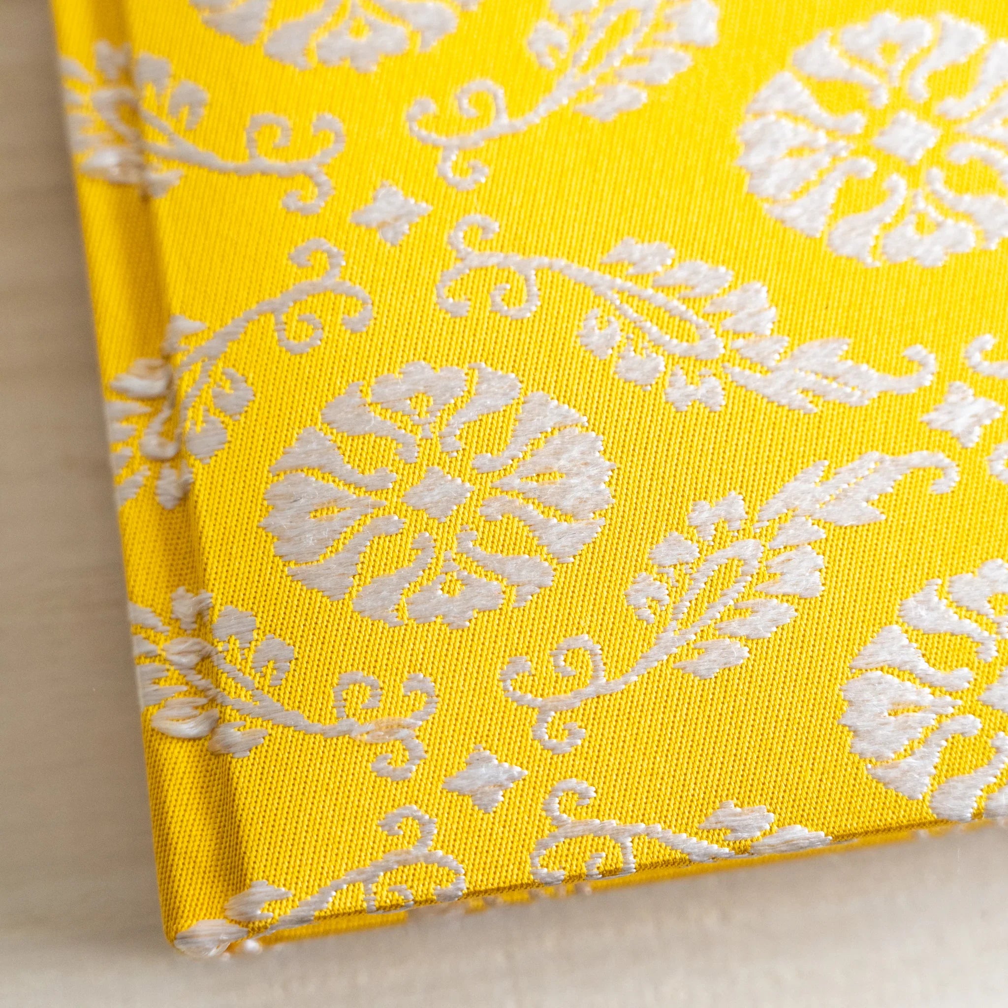 Macro detail of Ko Aoi Nishijin silk weave showing fine thread texture with golden background and cream Ko Aoi floral motifs