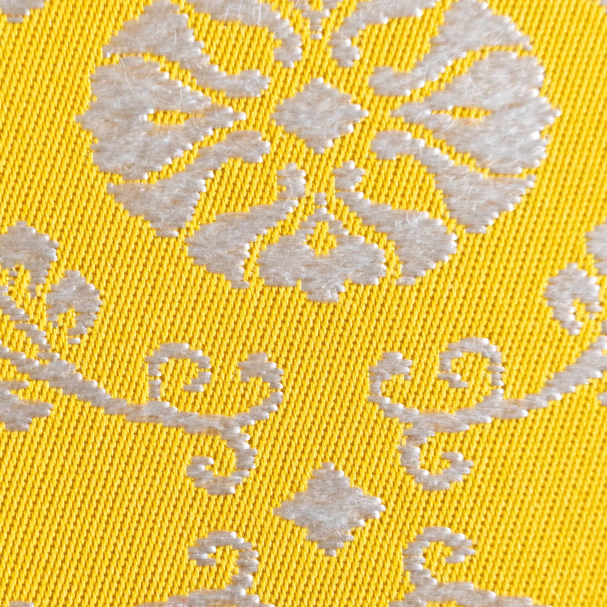 Extreme macro of Ko Aoi Nishijin silk showing individual thread weave structure with raised cream floral motifs on gold