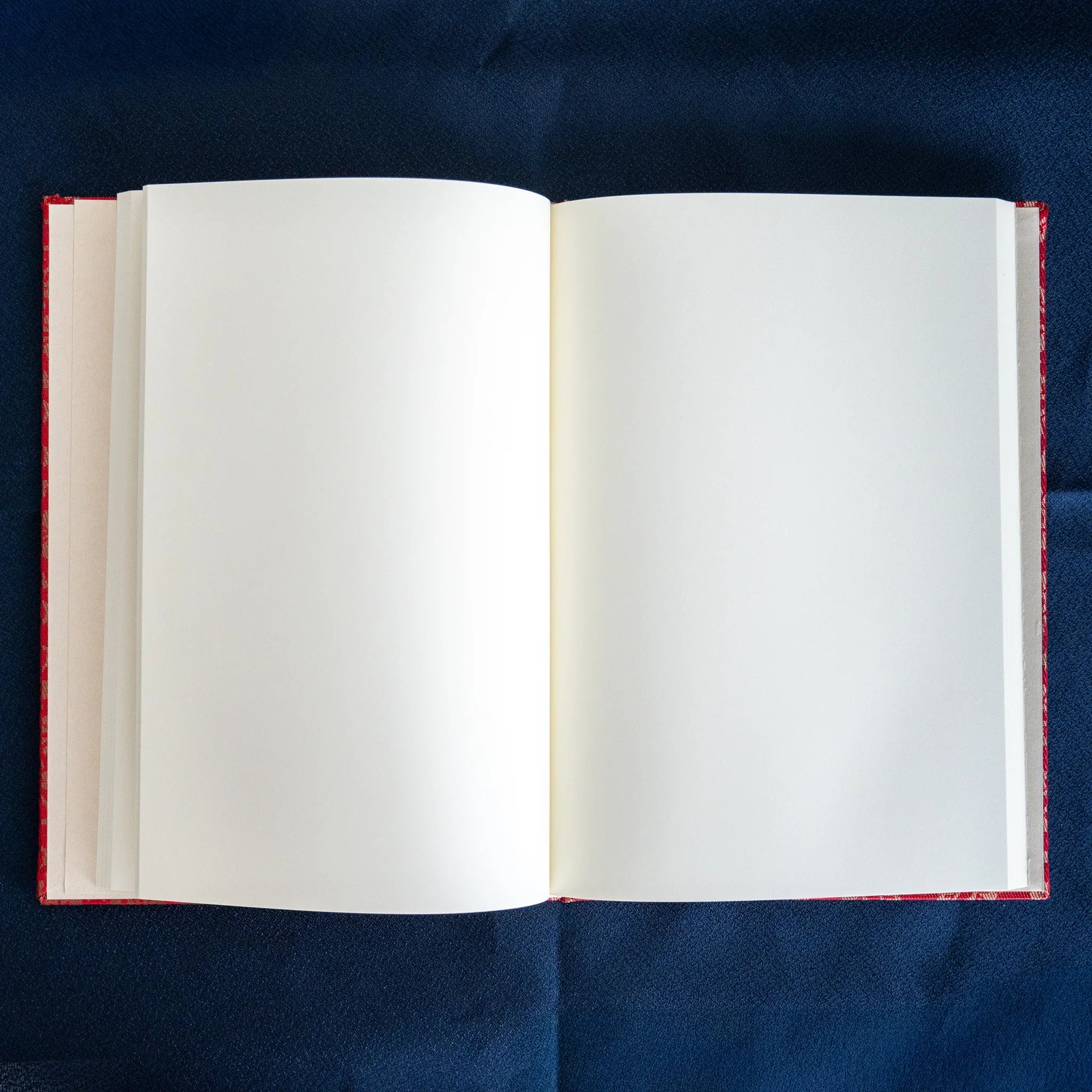 Ko Aoi Nishijin silk Homeicho notebook opened showing blank pages from above with vermilion cover edges framing the spread