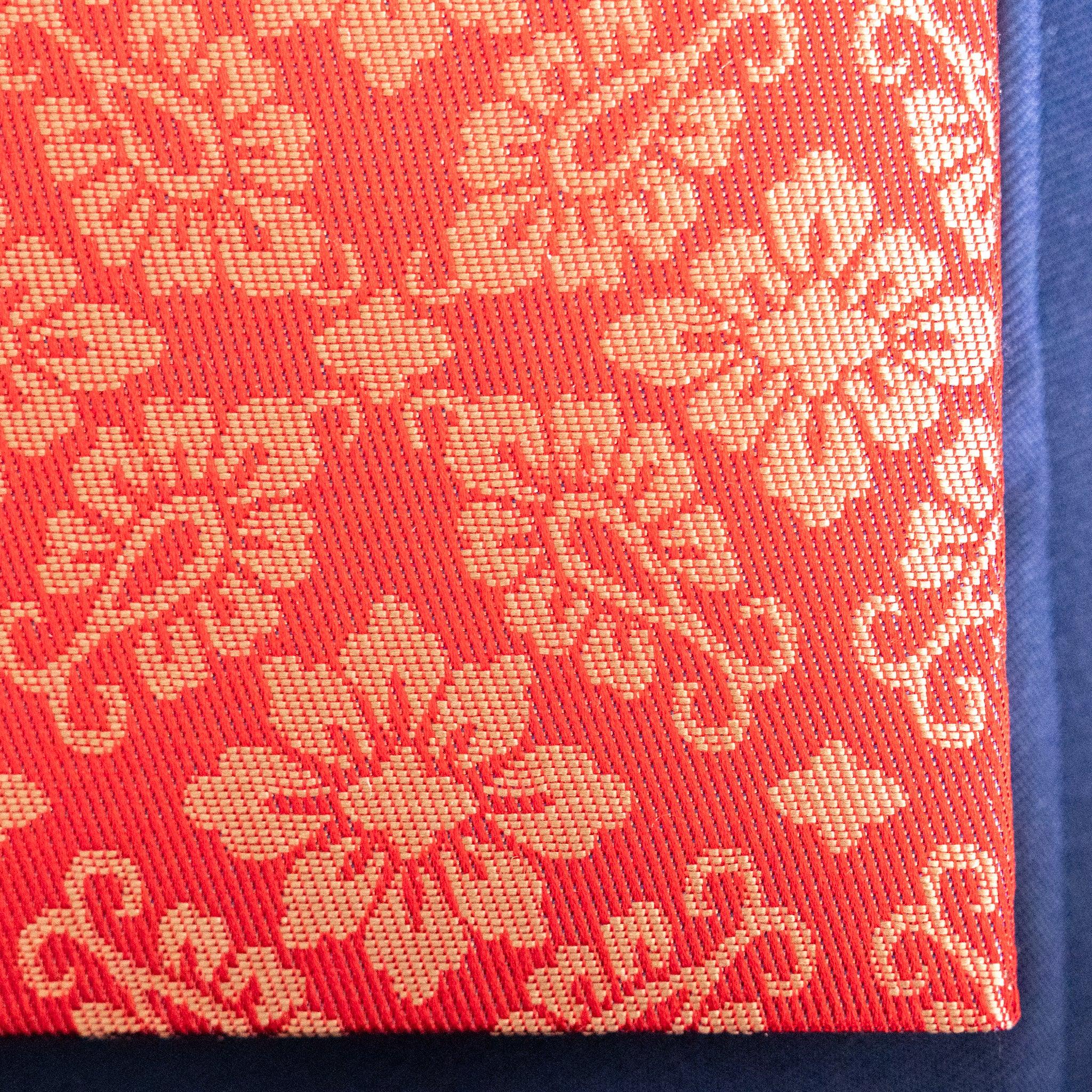 Ko Aoi Nishijin silk Homeicho notebook cover close-up showing vermilion hollyhock pattern with spine edge on blue fabric