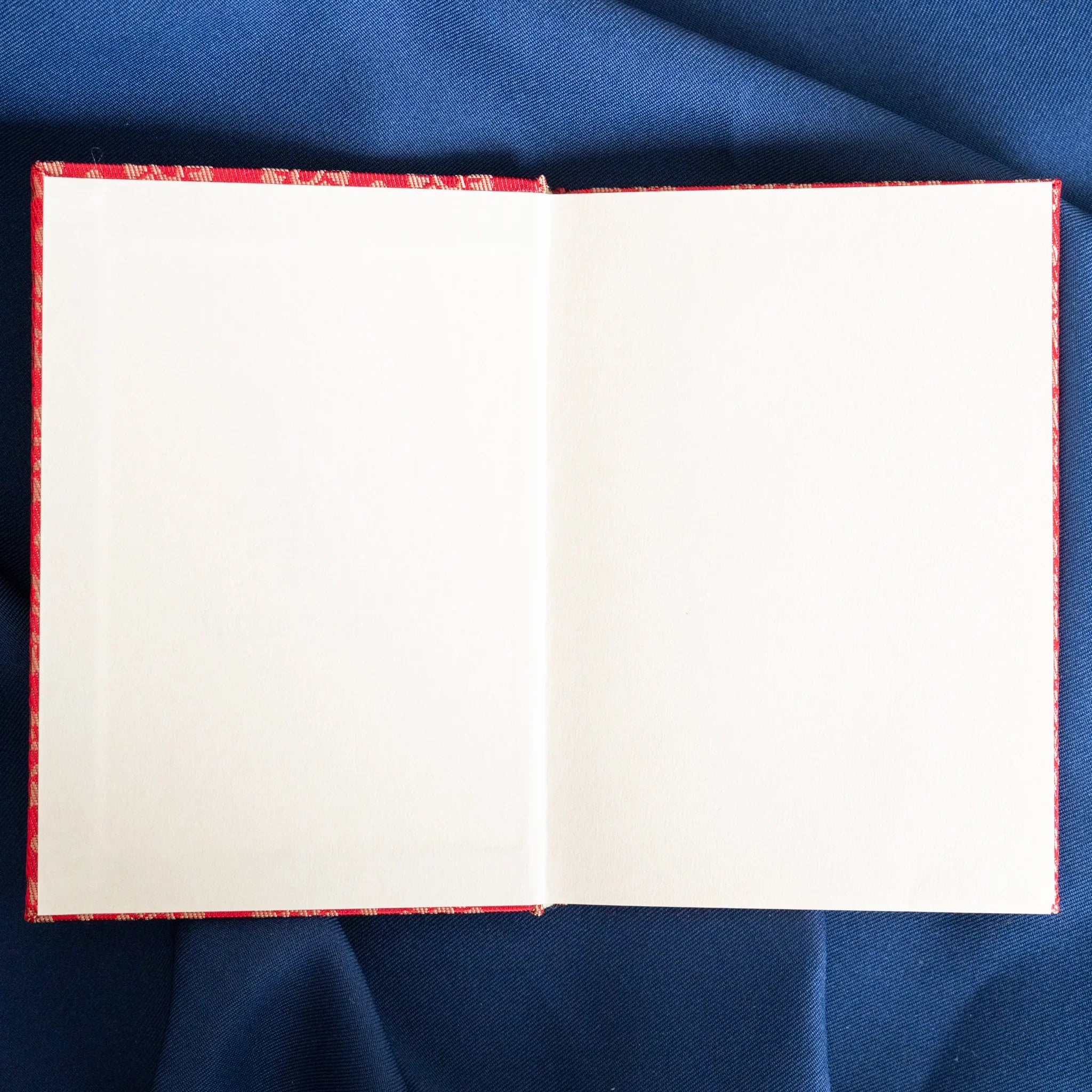 Ko Aoi Nishijin silk Homeicho notebook opened flat overhead showing blank white pages bordered by vermilion Ko Aoi cover