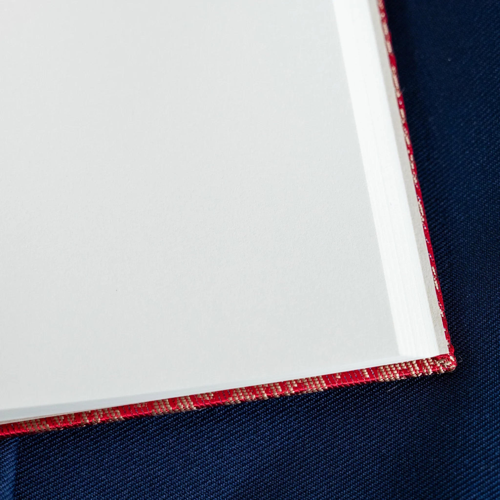 Ko Aoi Nishijin silk notebook angled corner detail showing white page stack edges with vermilion Ko Aoi cover binding