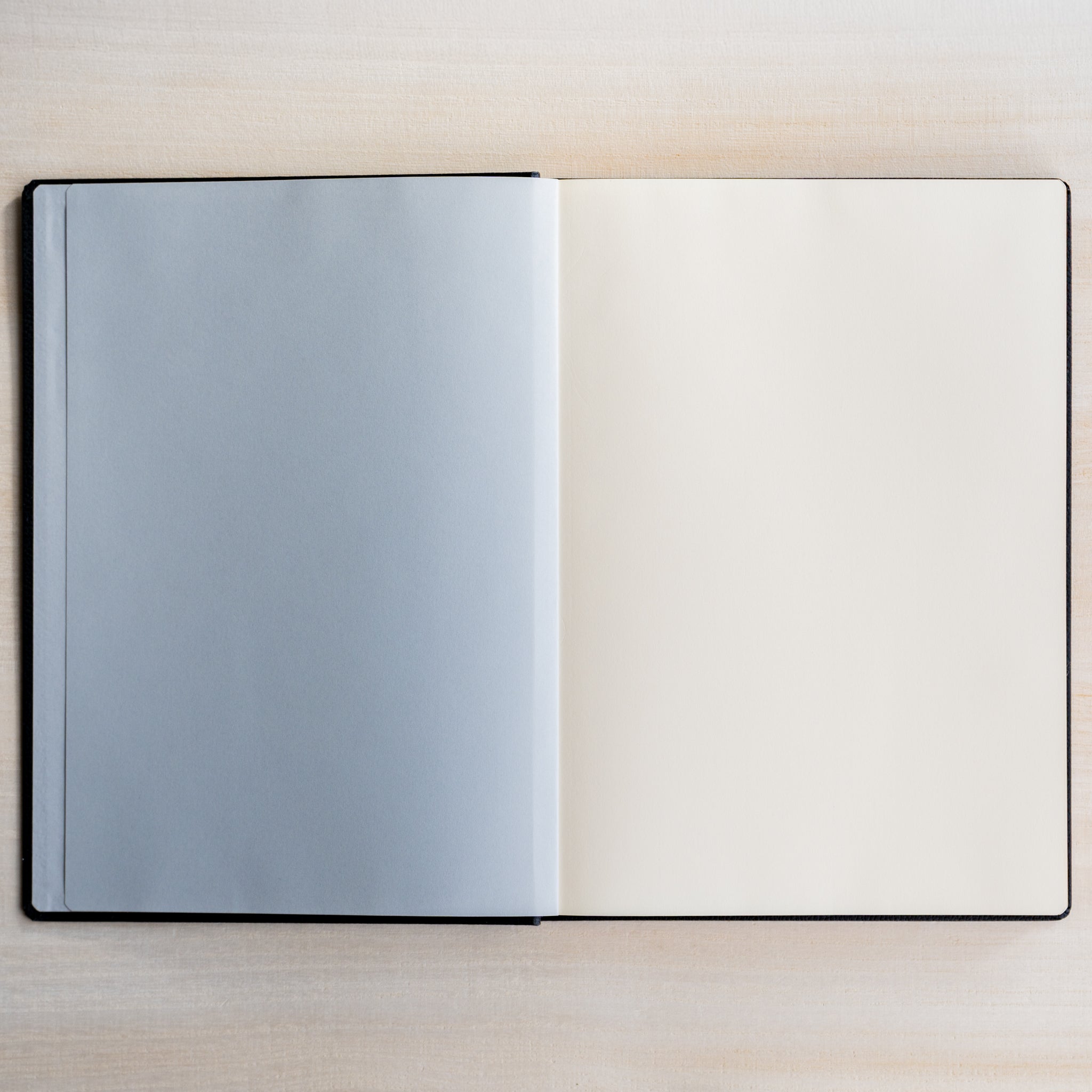 Life Noble notebook A5 open on desk, showing pale gray flyleaf and cream pages, ideal for journaling and neat writing