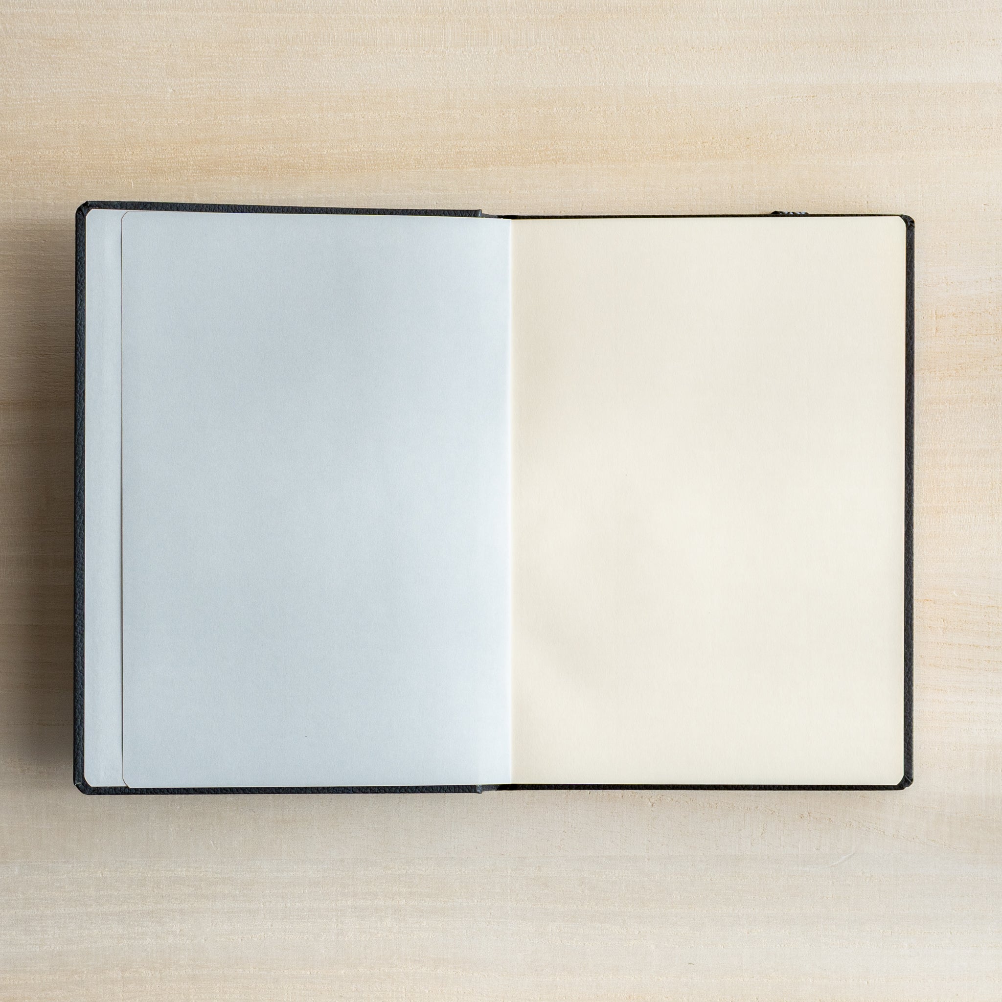 Life Noble notebook A6 open flat on desk, showing pale gray flyleaf and cream L Writing Paper for fountain pen writing