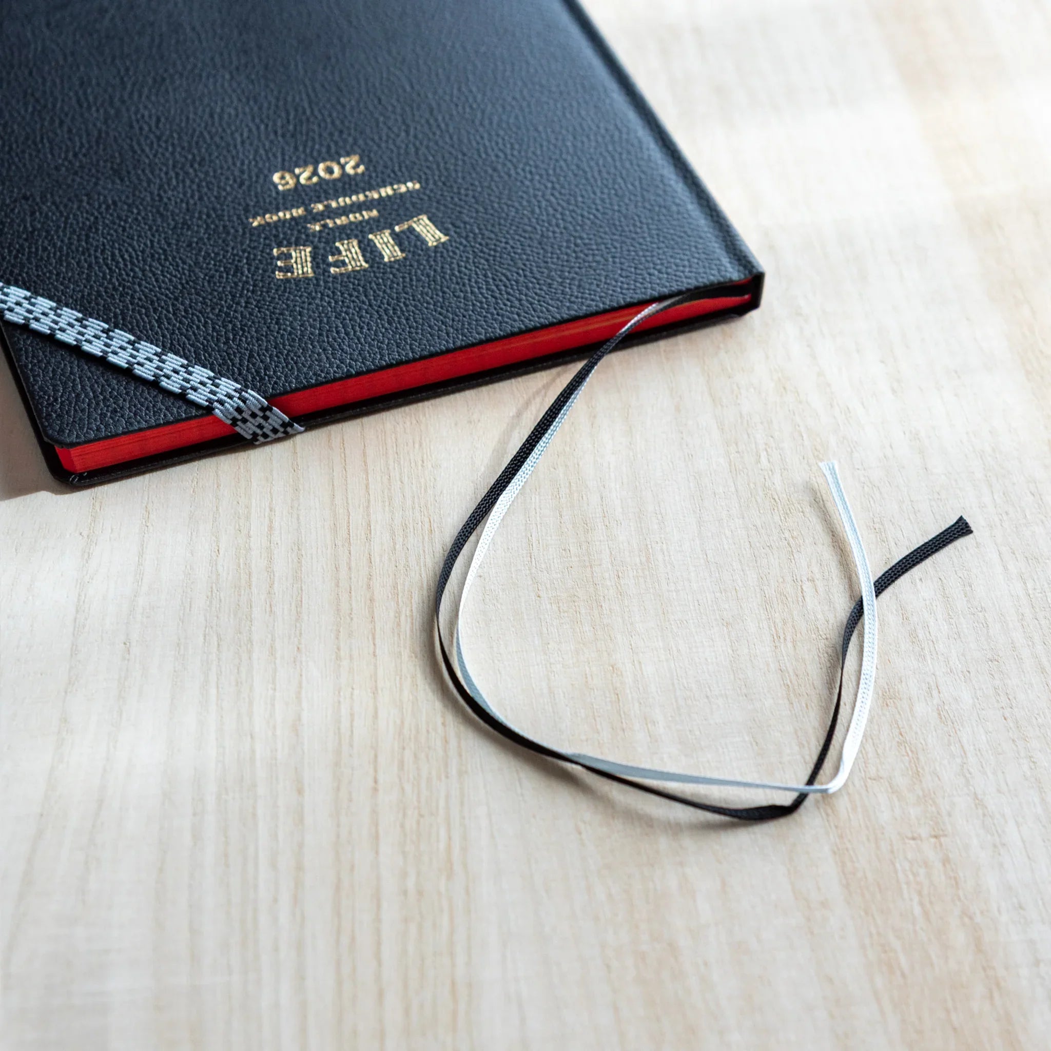 Life Noble Planner 2026, Japanese Planner showing black and white ribbon bookmarks and red-edged pages.