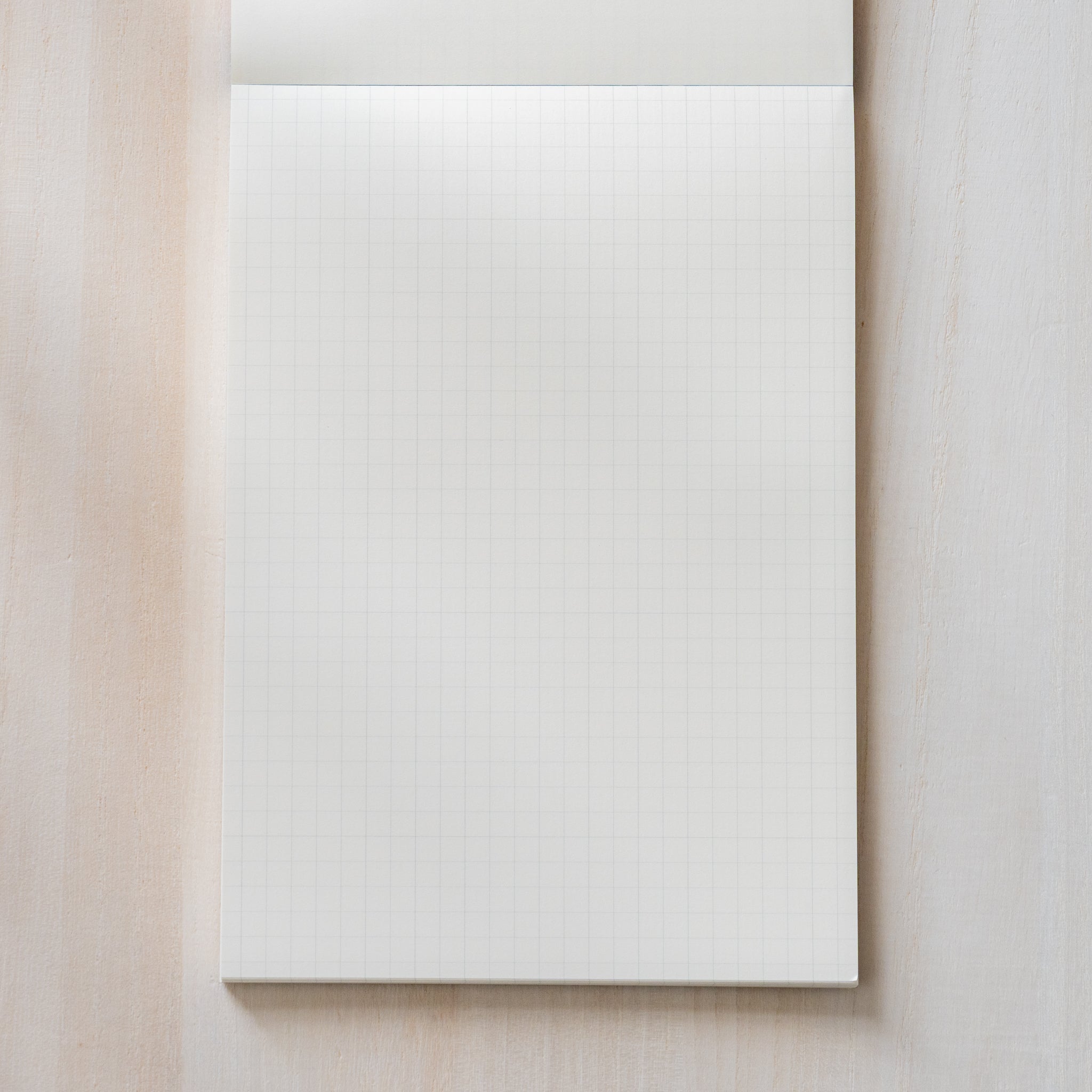 Life noble writing pad B6 grid page shown flat, cream L Writing Paper with fine squares, paper gently curled to show texture