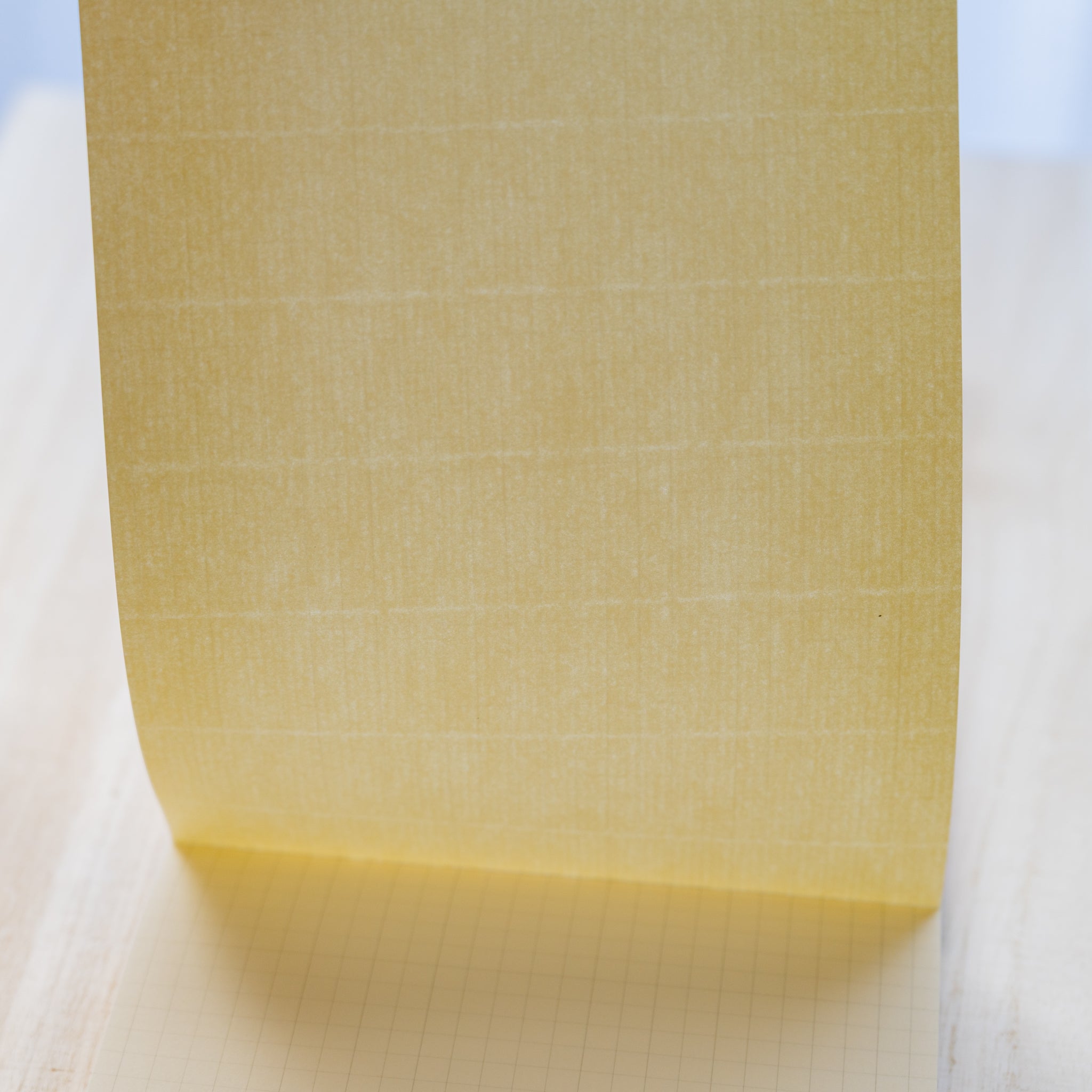 Life noble writing pad B6 close-up showing cream L Writing Paper lifted upright, subtle texture and grid page visible beneath