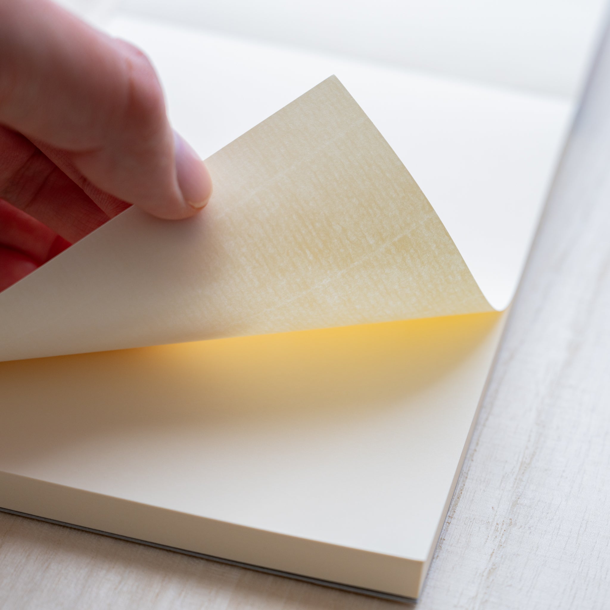 Life noble writing pad B6 close-up showing smooth cream L Writing Paper thickness, page gently lifted to reveal texture