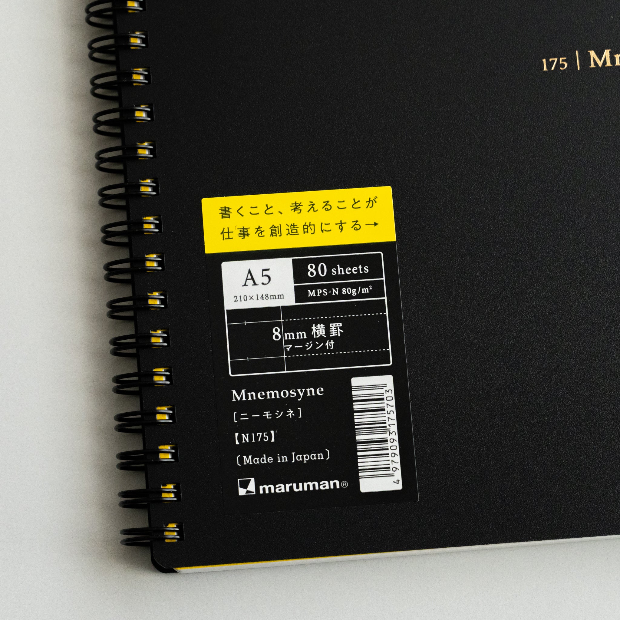 Close-up of Maruman Mnemosyne lined notebook cover with black twin-ring binding and detailed A5 product label for 80 sheets.