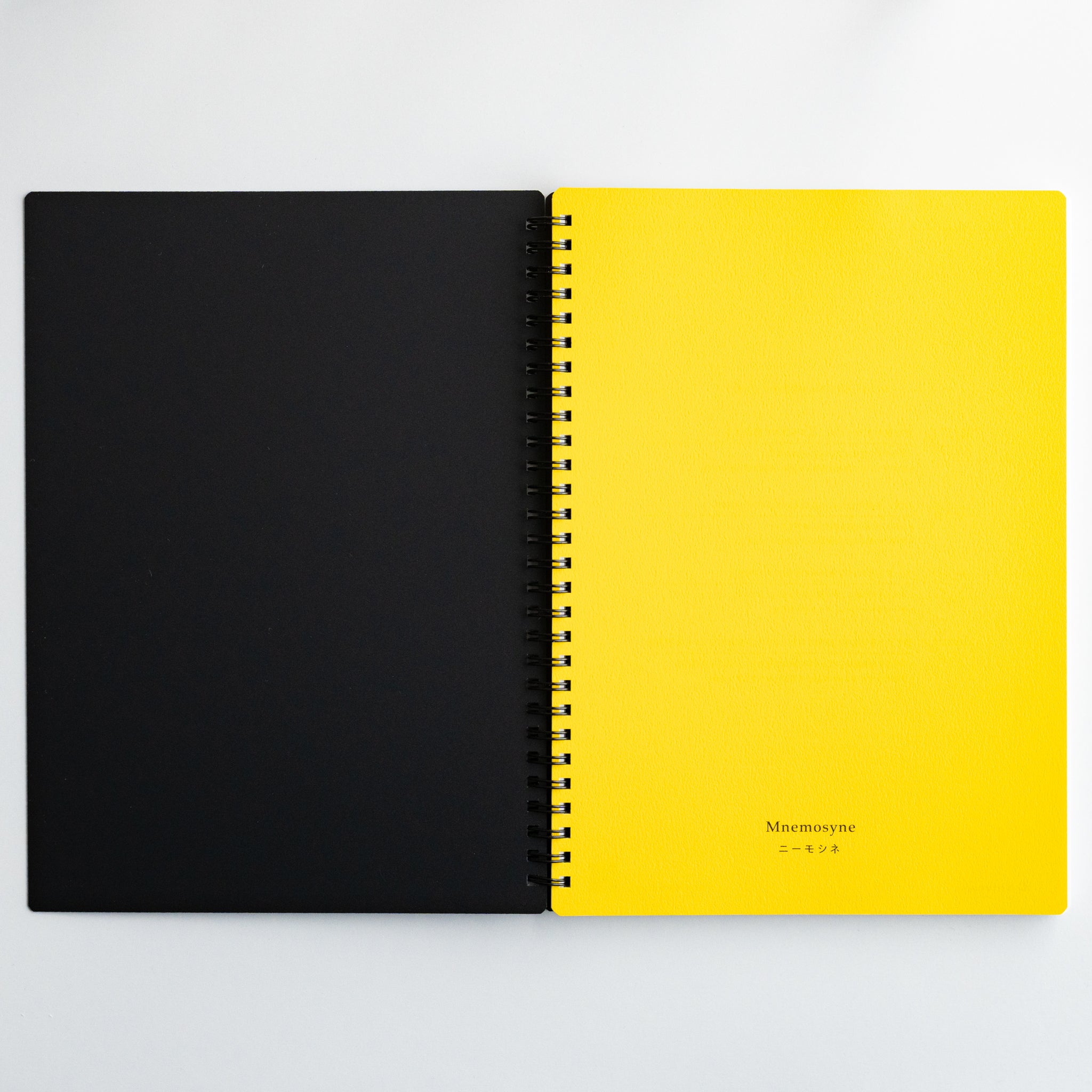 Open Maruman Mnemosyne notebook with black and yellow pages and twin-ring binding for sleek and modern writing.