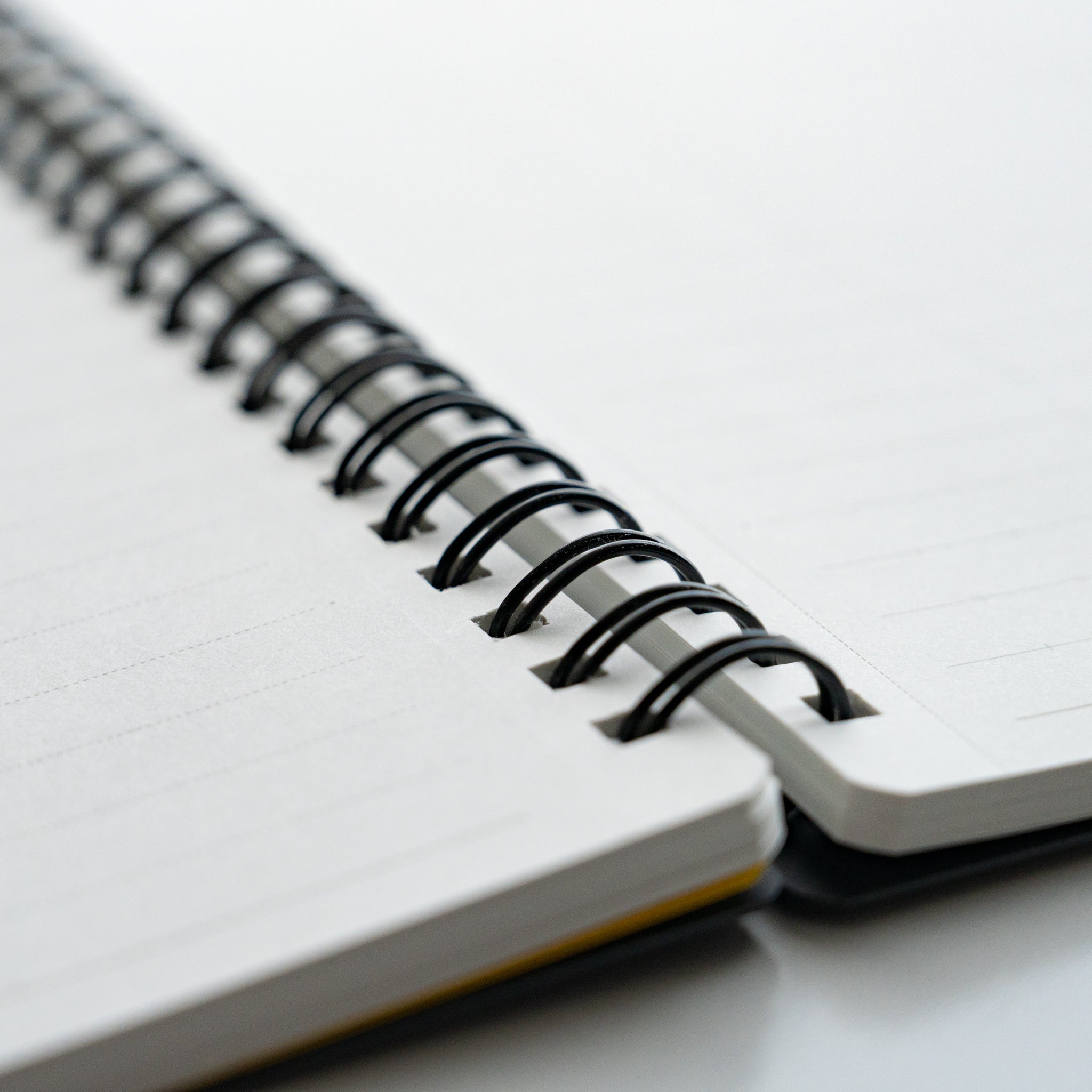 Close-up of Maruman Mnemosyne notebook's spiral binding connecting blank pages, highlighting craftsmanship.