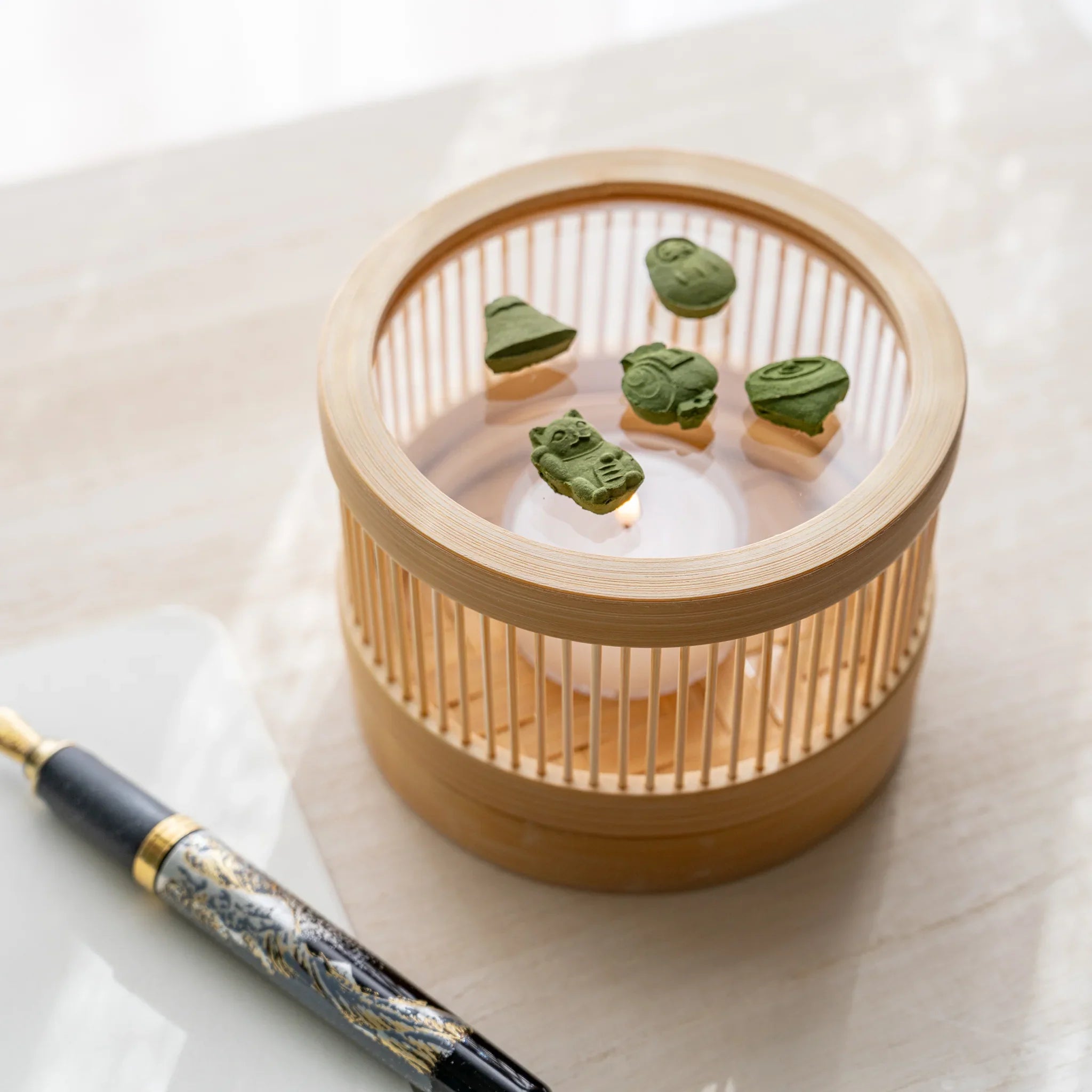 Suruga bamboo matcha incense tea warmer with five pressed matcha pieces on glass plate and lit tealight inside