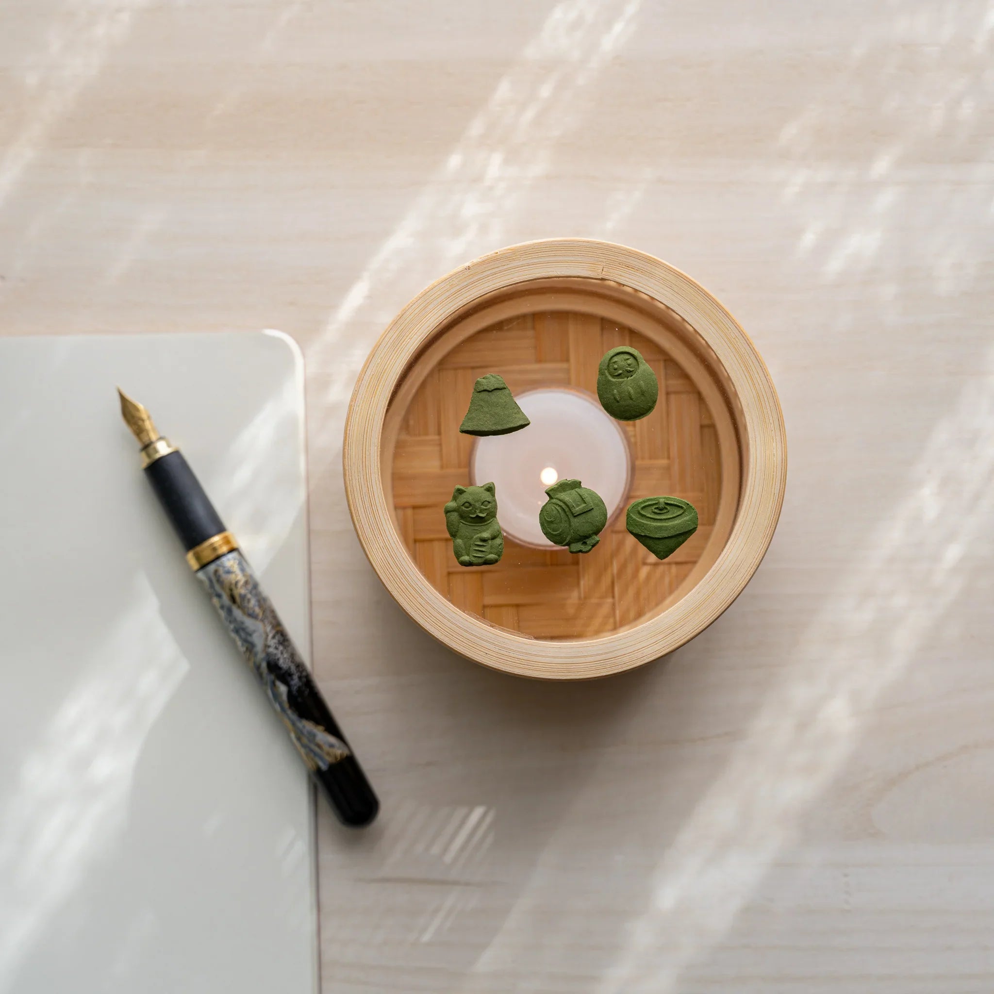 Top-down view of Suruga bamboo matcha incense warmer with five pressed matcha pieces around a lit tealight