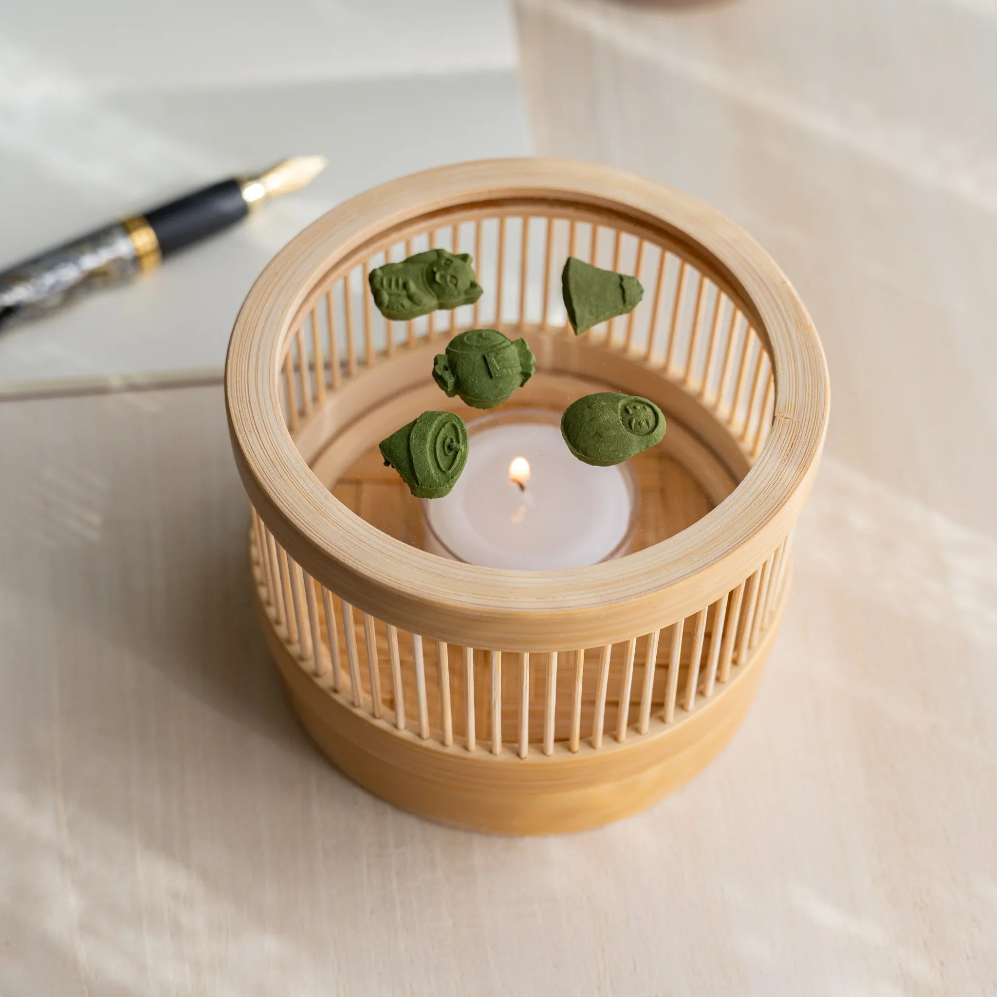 Suruga bamboo matcha incense tea warmer with five pressed matcha pieces inside, fountain pen beside