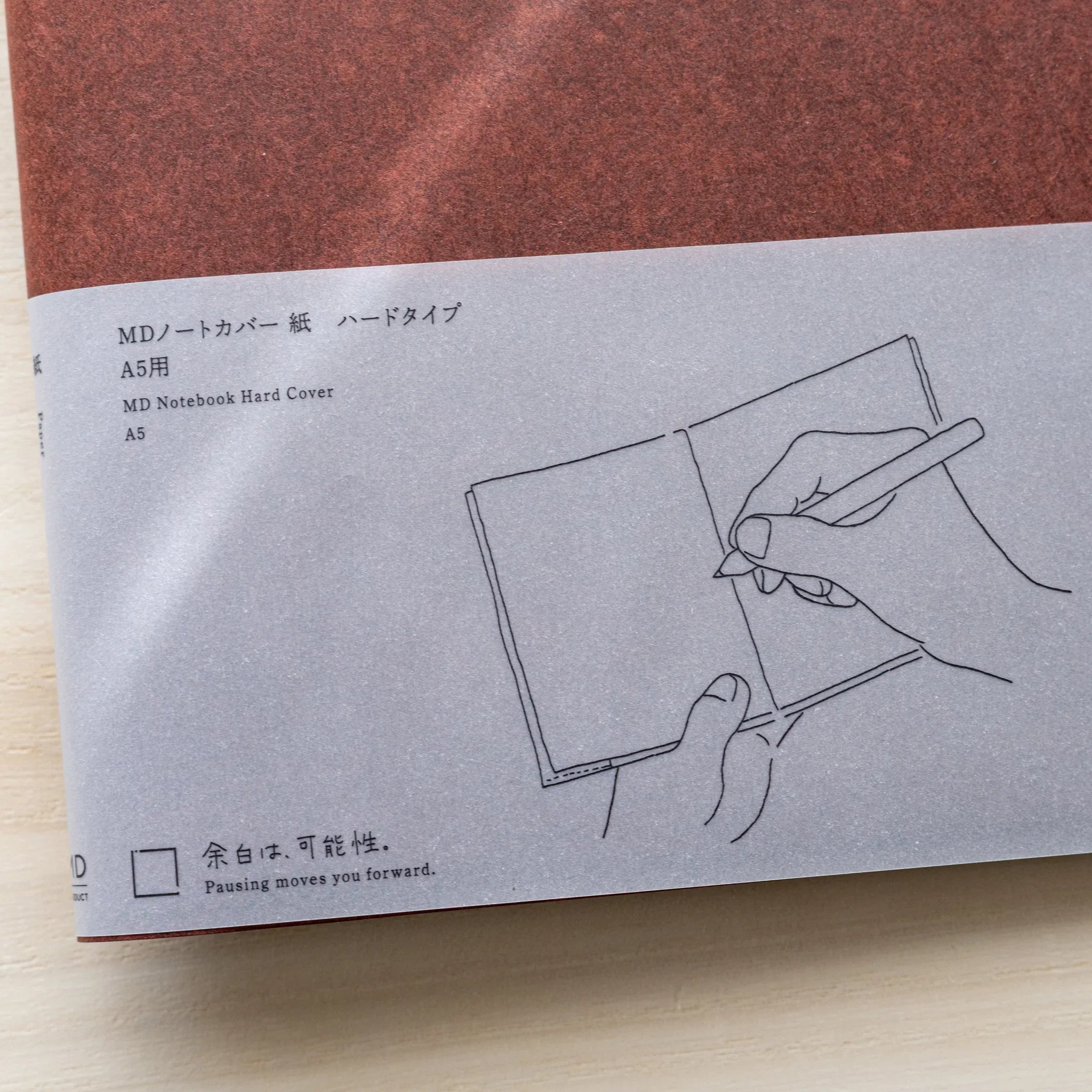 Close-up of Midori MD Notebook Hard Cover A5 gray belly band showing Japanese and English text and hand writing illustration