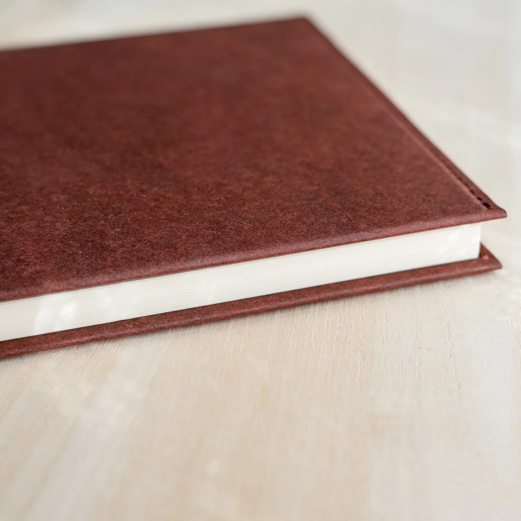 Midori MD Notebook Hard Cover corner close-up, dark red hard paper surface with white notebook pages visible at bottom