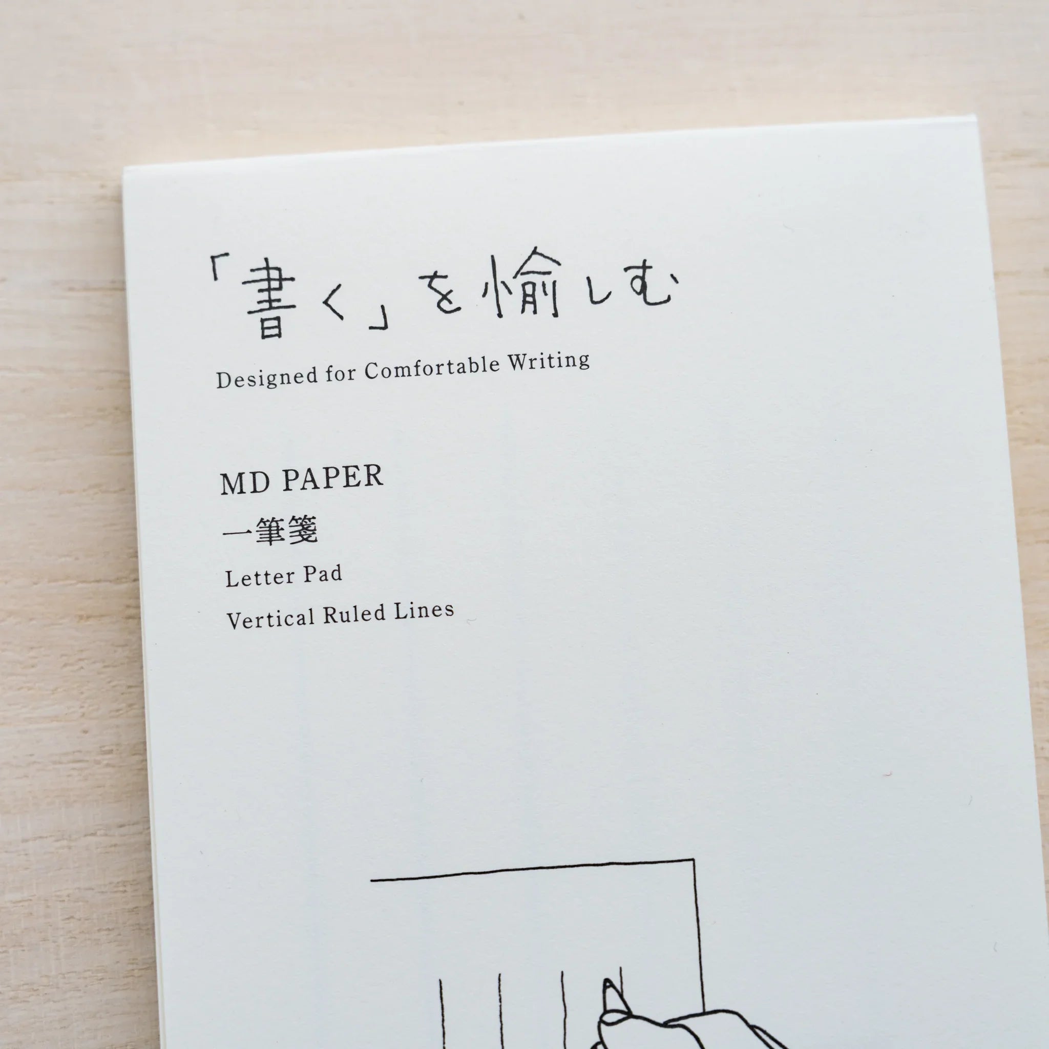 Close-up of an MD Paper letter pad cover reading MD Paper Letter Pad Vertical Ruled Lines with hand illustration