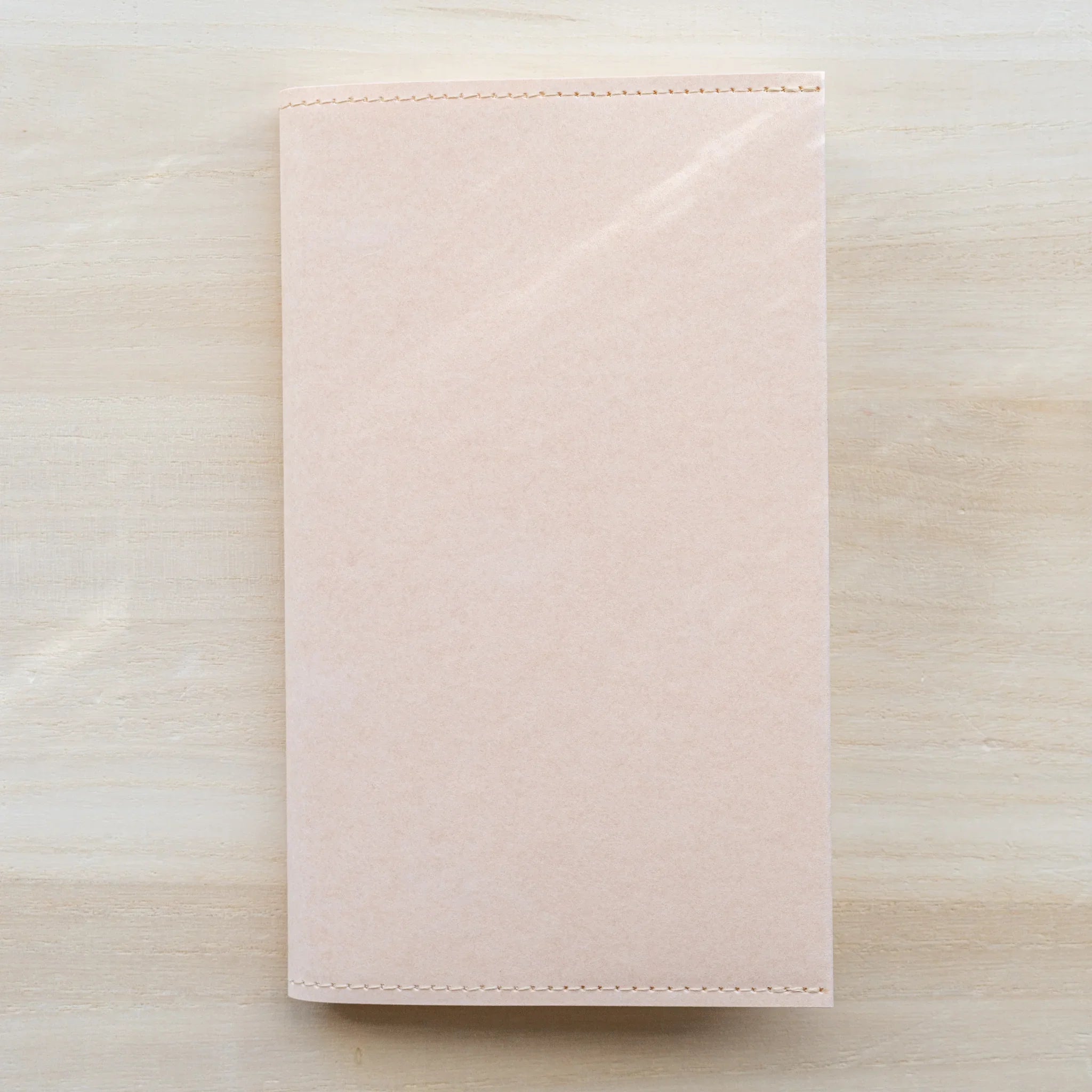 Midori MD Paper Notebook Cover A5 closed front view on wooden surface, pale paper with stitched top edge
