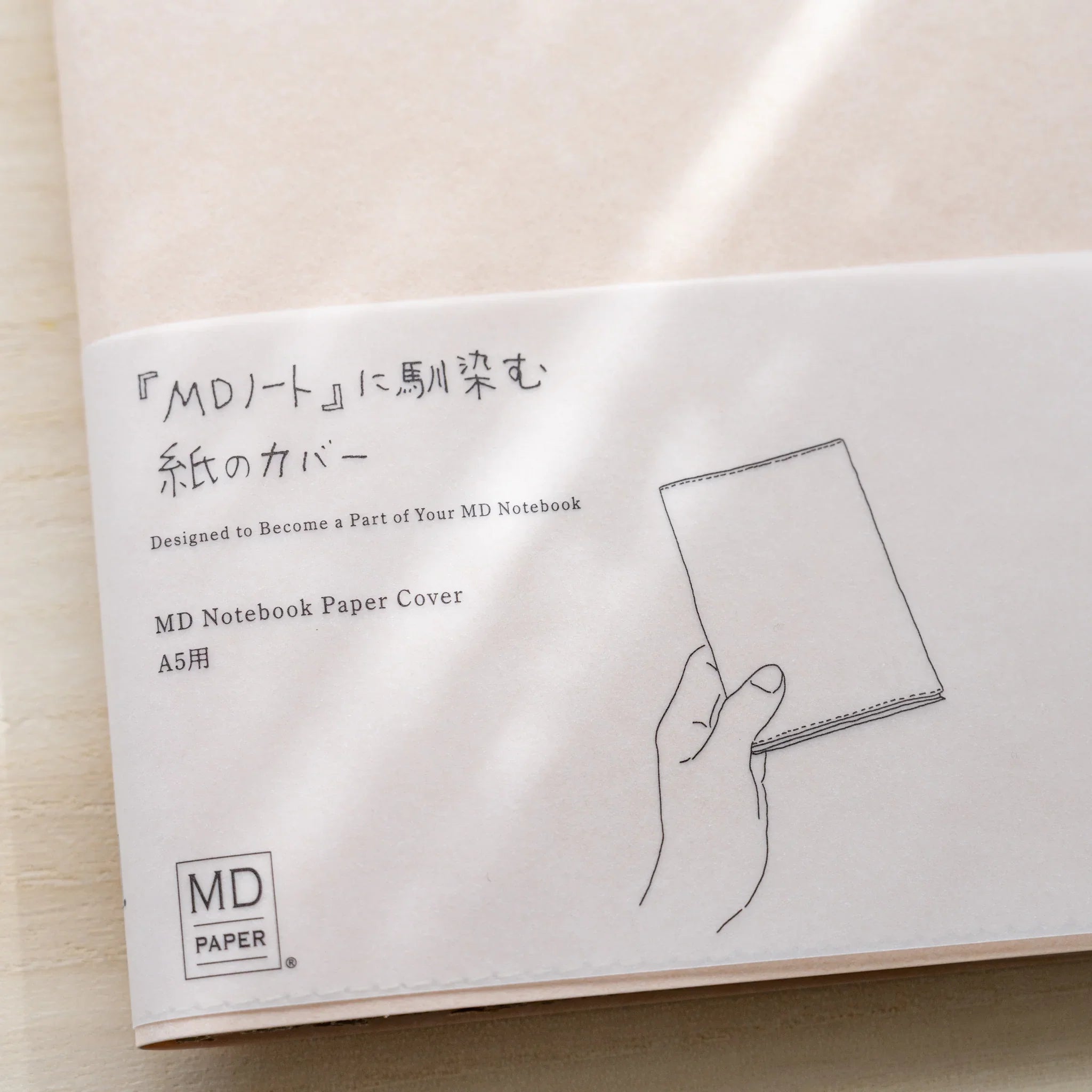 Close-up of Midori MD Notebook Paper Cover A5 belly band showing Japanese and English text and hand illustration