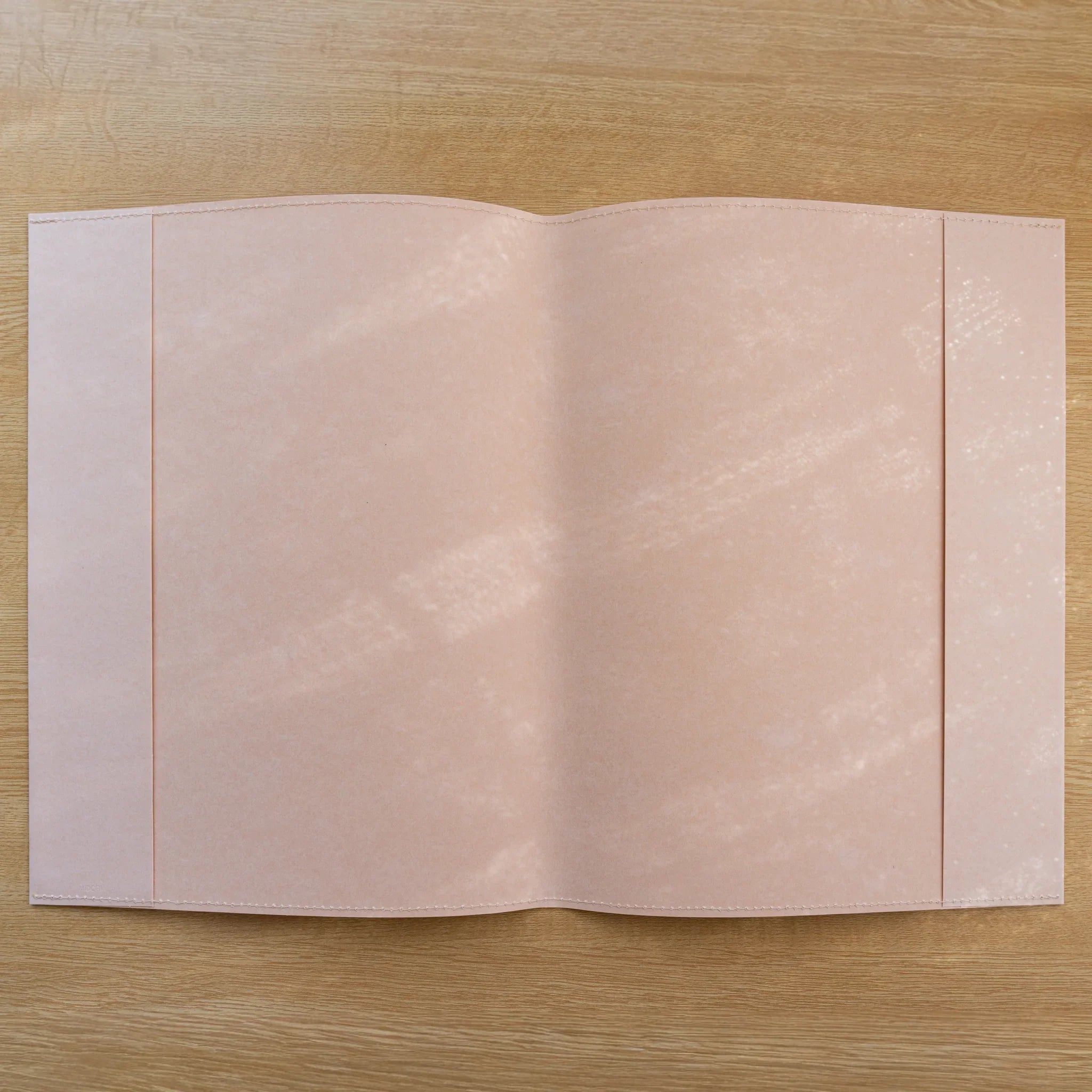 Pale pink MD Notebook Paper Cover opened flat showing two panels on a wood surface