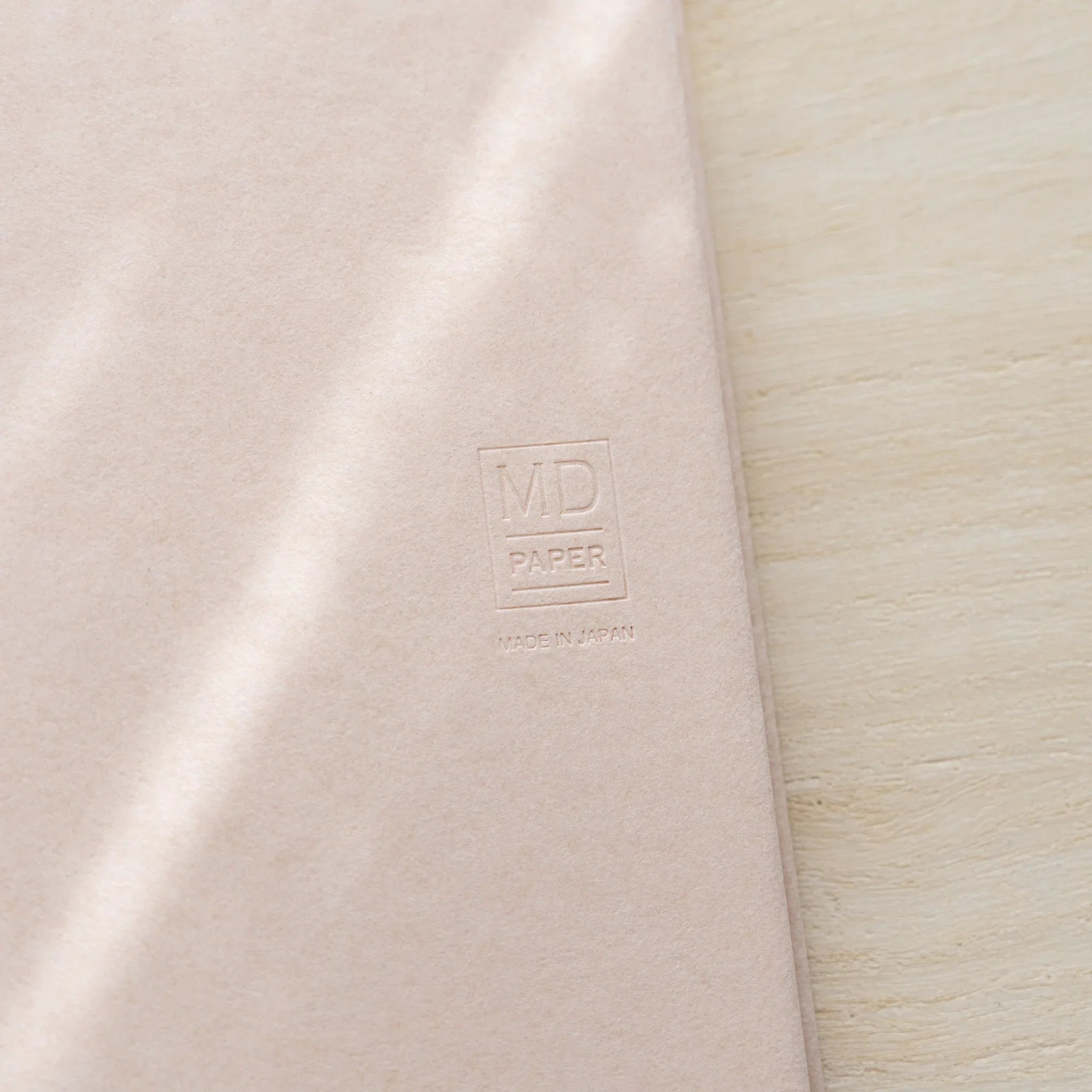 Midori MD Notebook Paper Cover back, close-up showing embossed MD Paper logo and Made in Japan text on pale paper surface