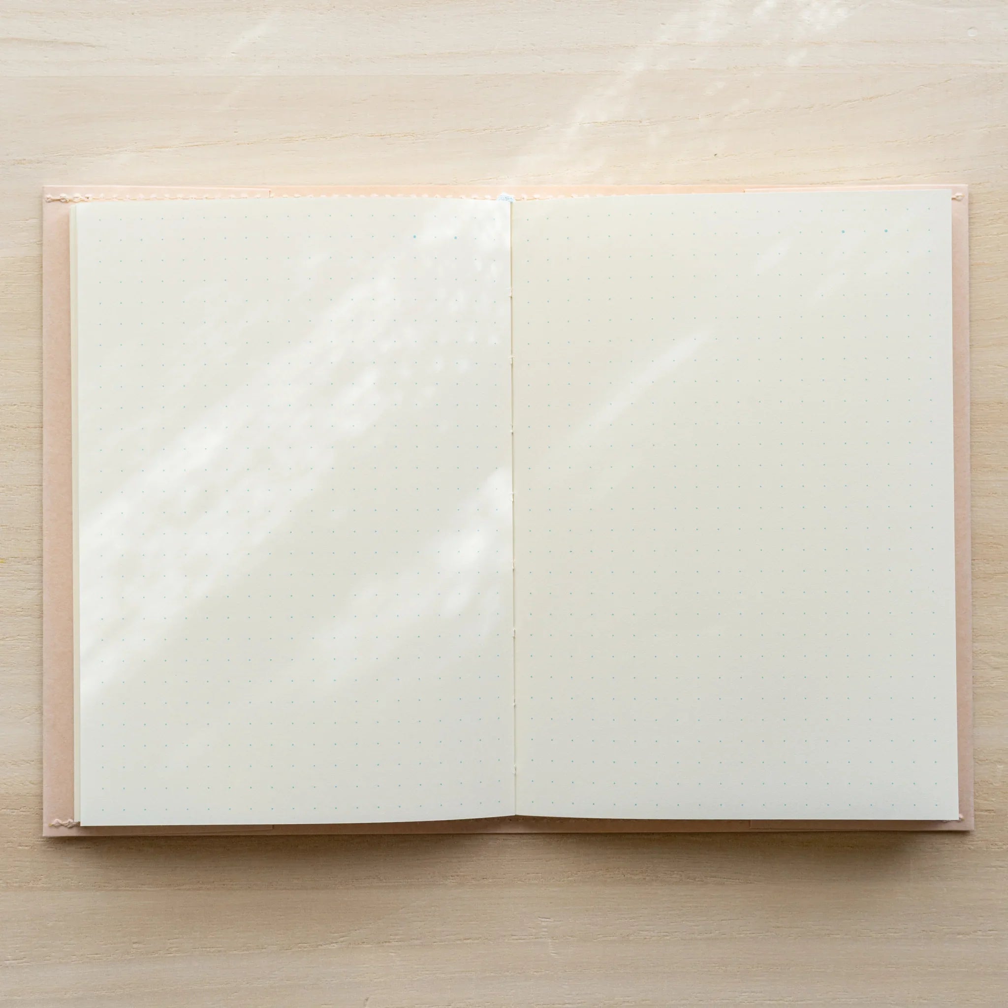 MD Paper Notebook Cover open flat on wooden surface with notebook inside, showing blank white spread and pale paper flaps