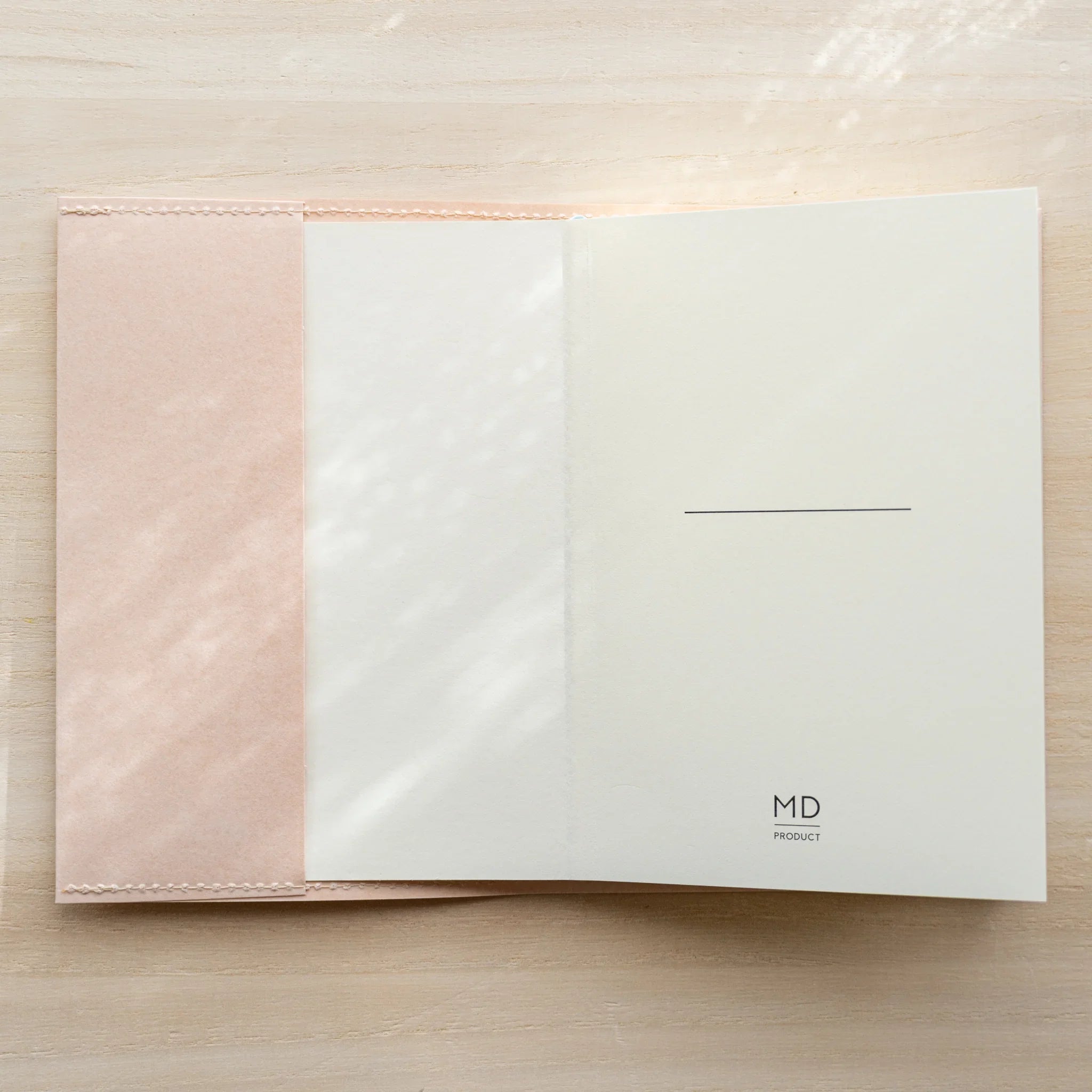 Notebook inside a pale pink MD Notebook Paper Cover, open showing a white spread with MD logo