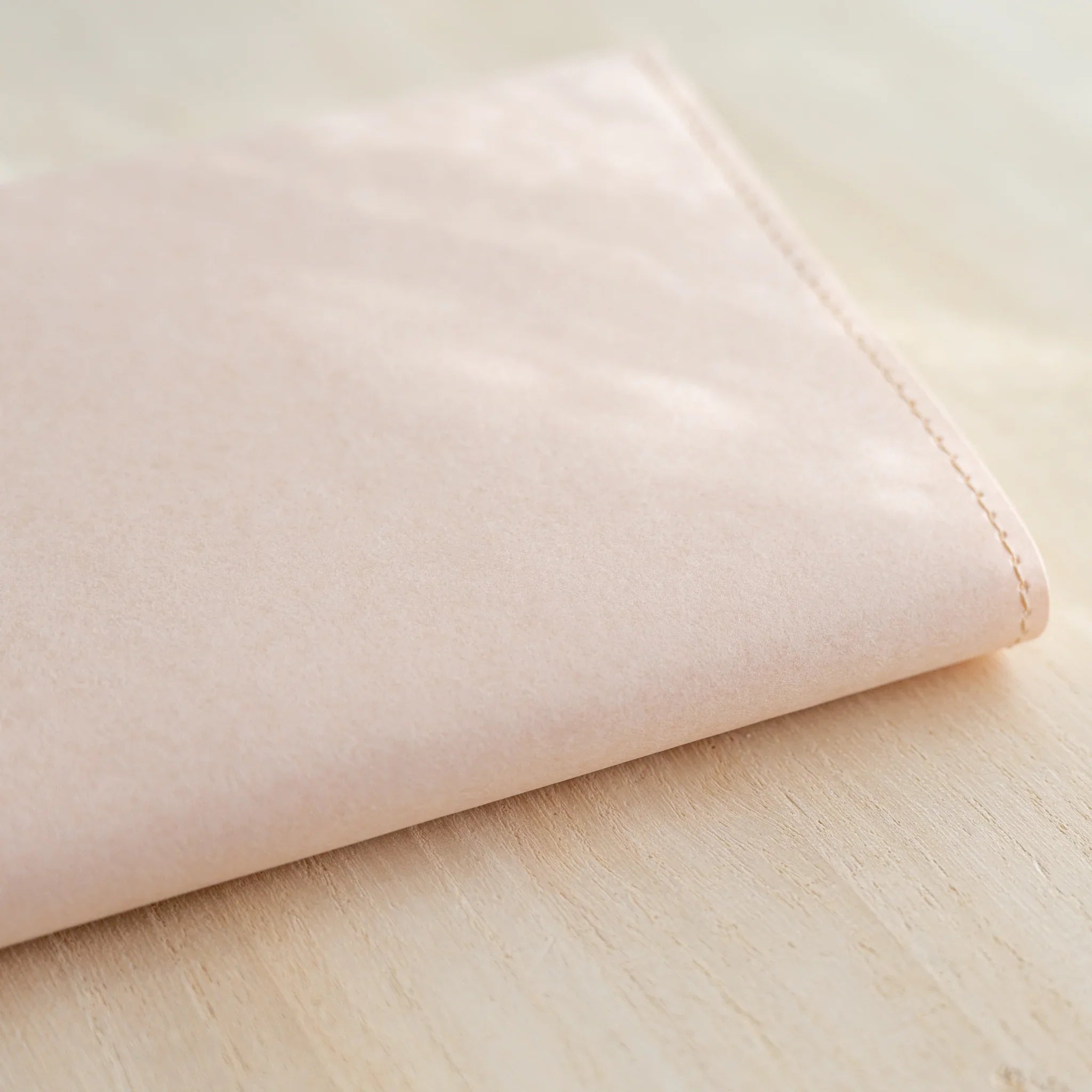 Folded pale pink MD Notebook Paper Cover seen at an angle showing the fold edge