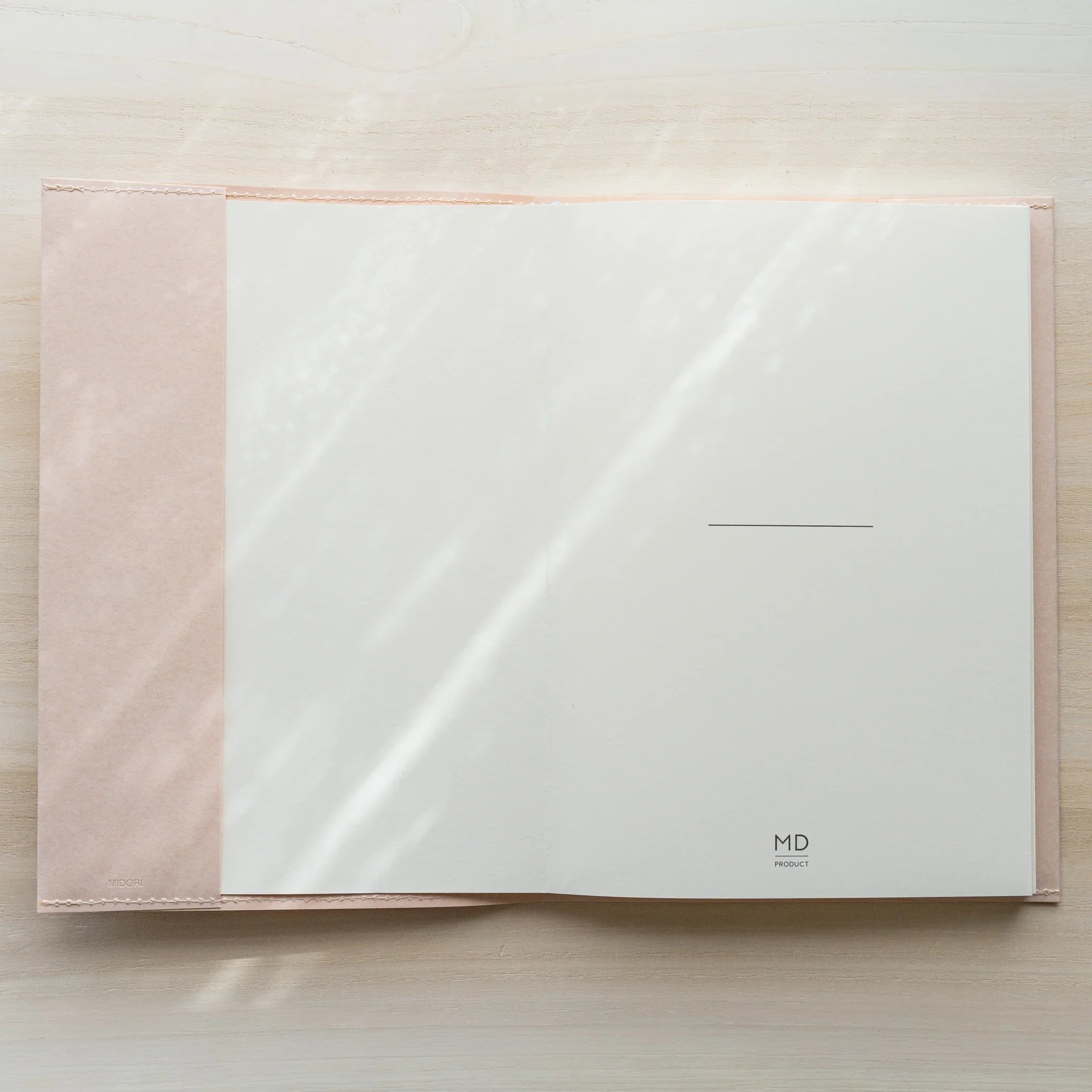 Midori MD Notebook Paper Cover opened flat from above, white inner panel with MD Project logo, pale paper flaps on sides