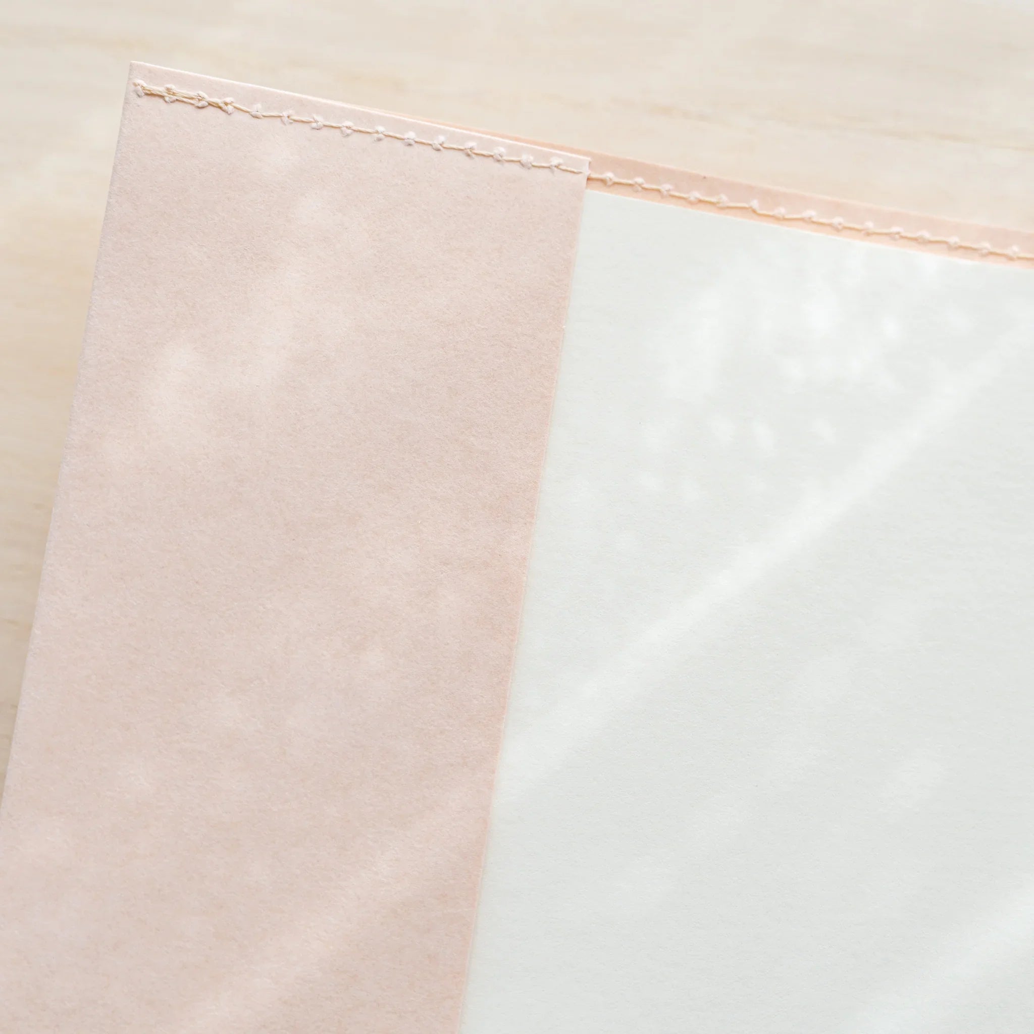 Midori MD Notebook Paper Cover corner close-up showing pale pink paper flap with stitched edge and white inner panel