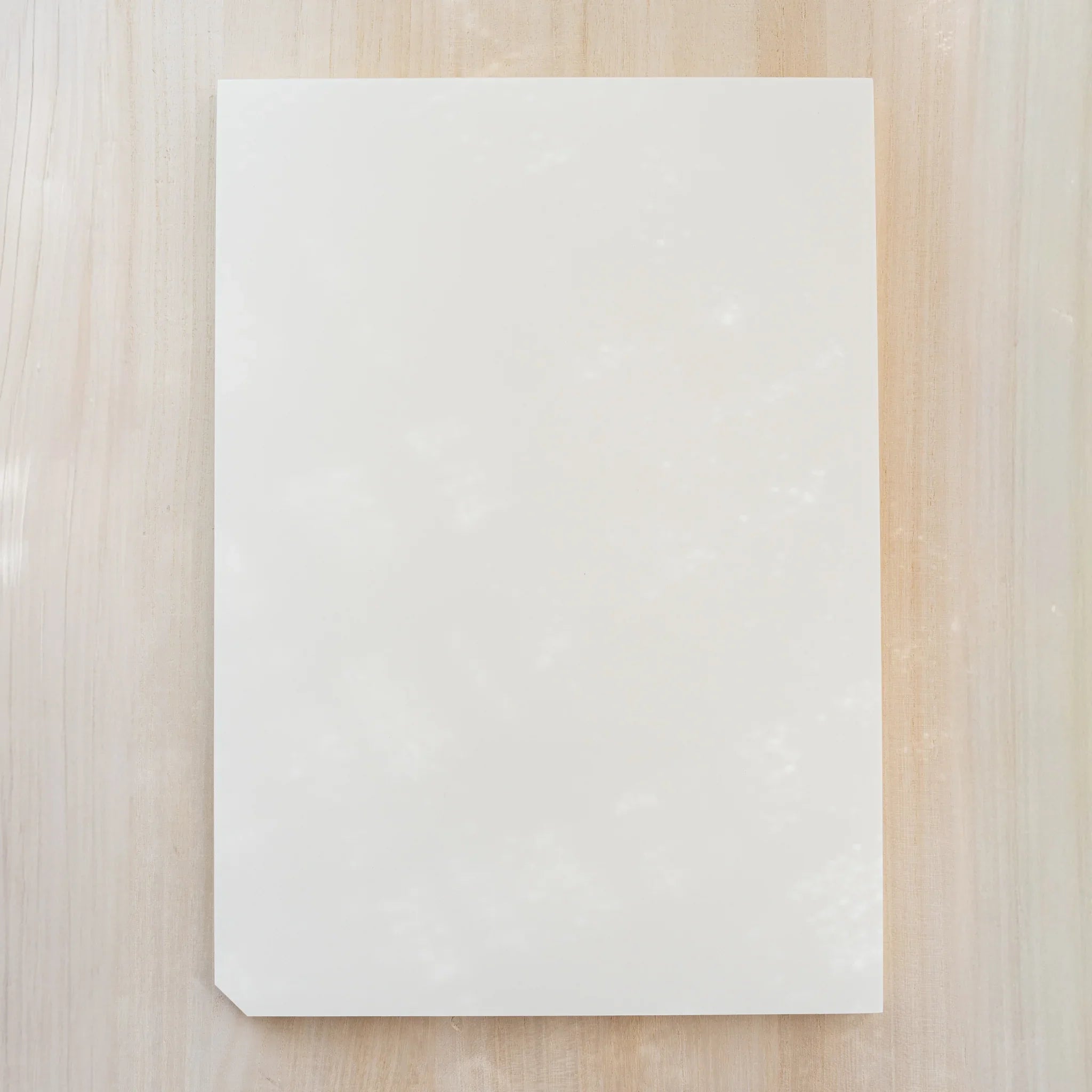 Midori MD Paper Pad A4, plain blank cream top sheet with one cut corner, no belly band, on light wood