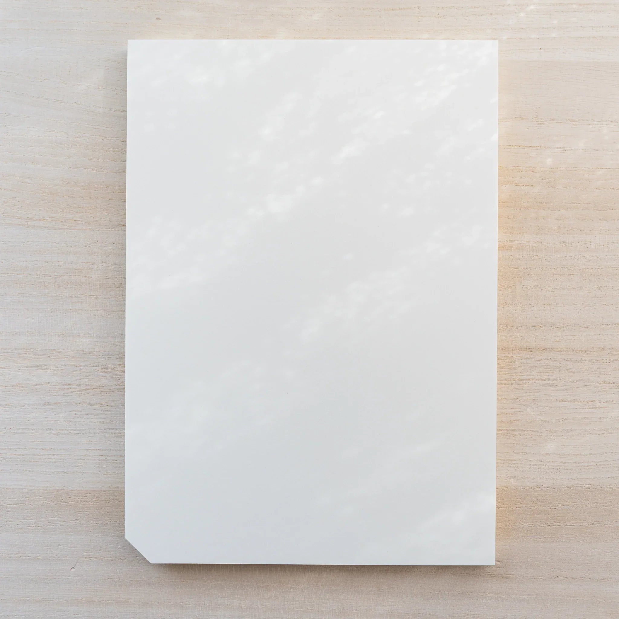Midori MD Paper Pad A5, plain blank white top sheet with one cut corner, no belly band, on light wood