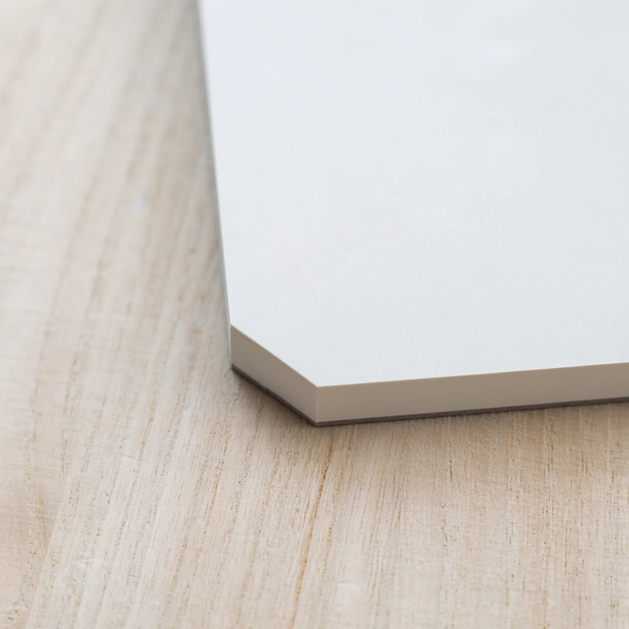 Close-up of the angled cut corner of a Midori MD Paper Pad Cotton A4 with page block on a gray backing board