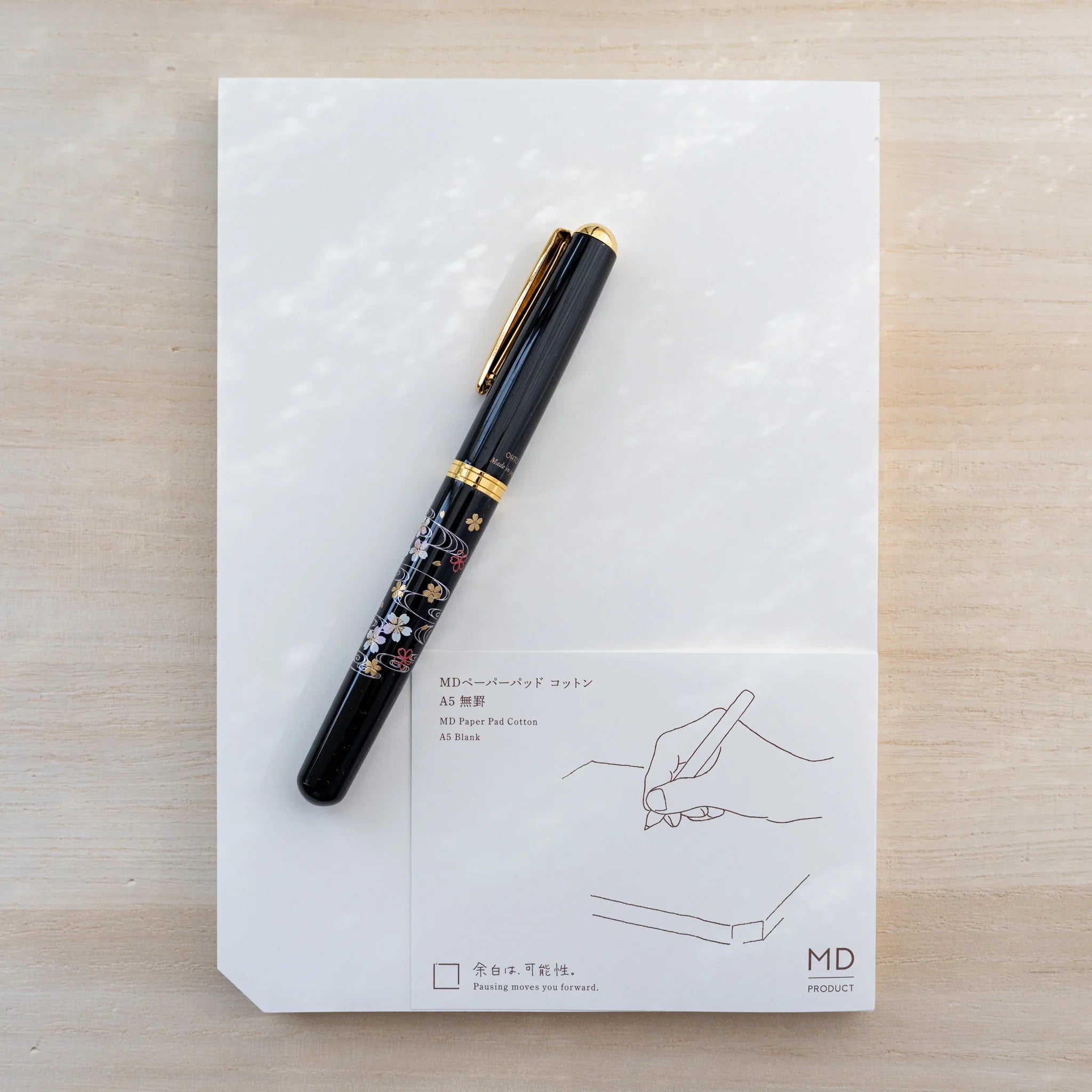 Midori MD Paper Pad Cotton A5 with brown belly band and a black gold-floral Japanese fountain pen resting on top