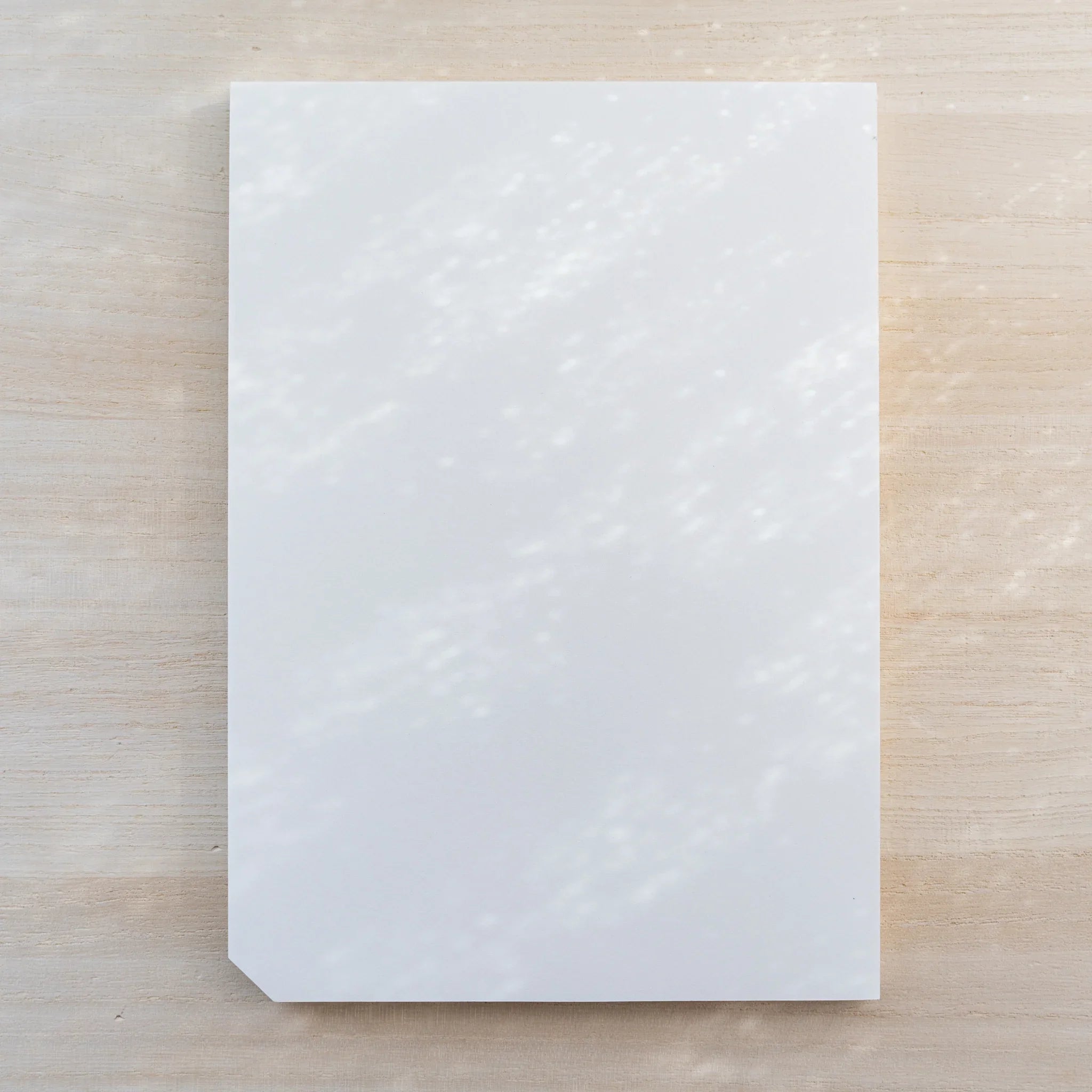 Midori MD Paper Pad Cotton A5, plain blank white top sheet with one cut corner, no belly band, on light wood